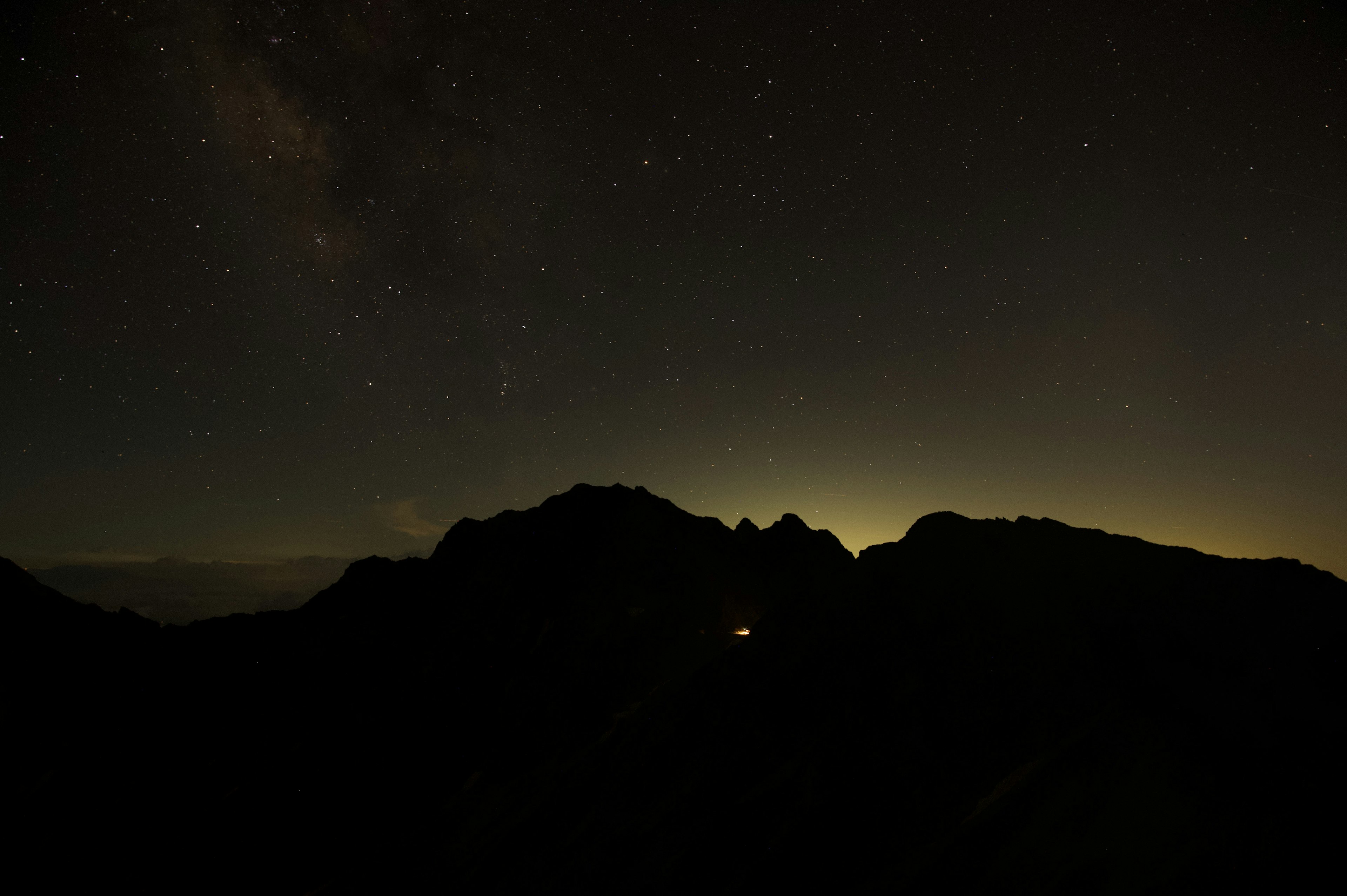 Paesaggio notturno con montagne silhouettate sotto un cielo stellato