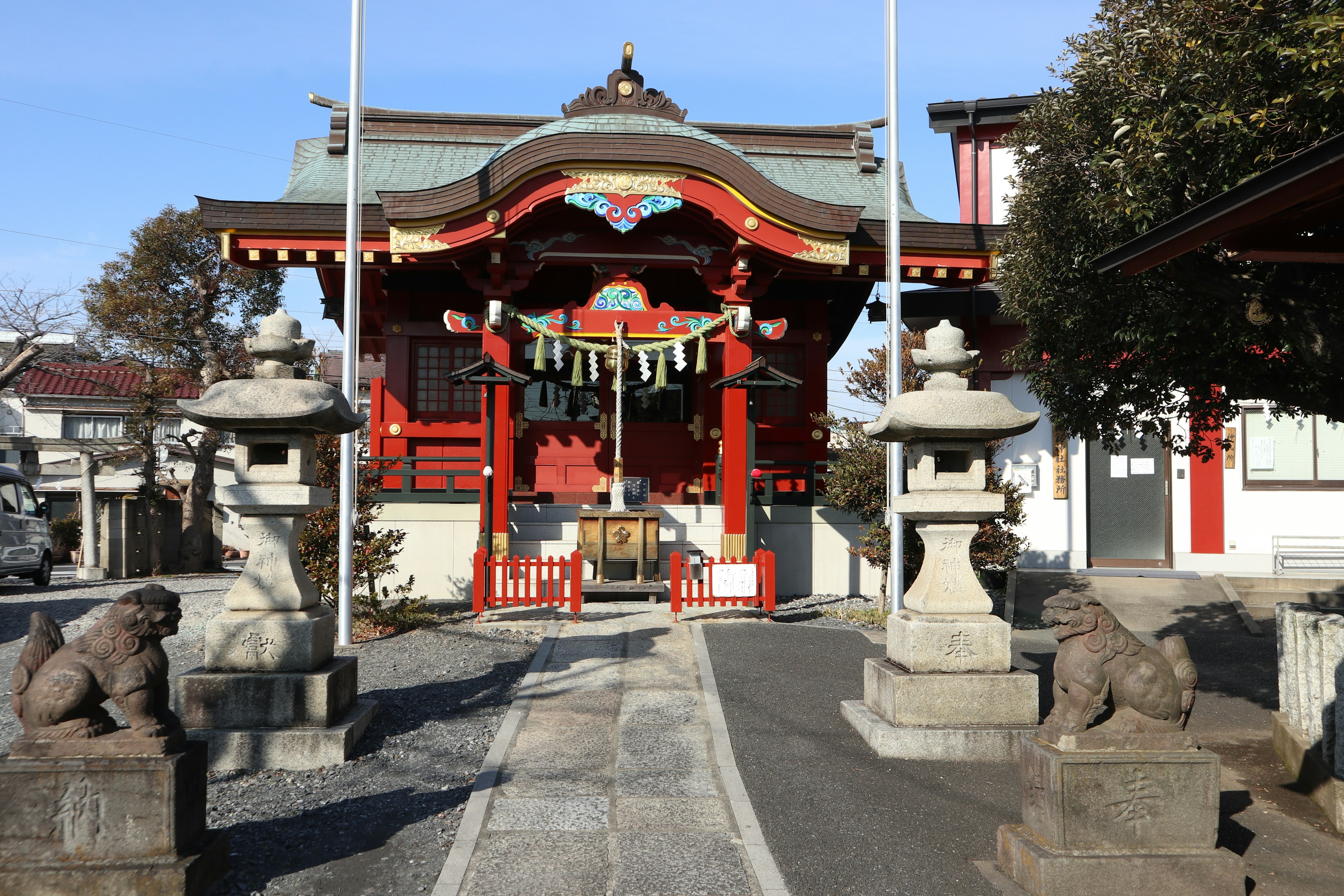 Entrance of a red shrine with stone lion statues on either side