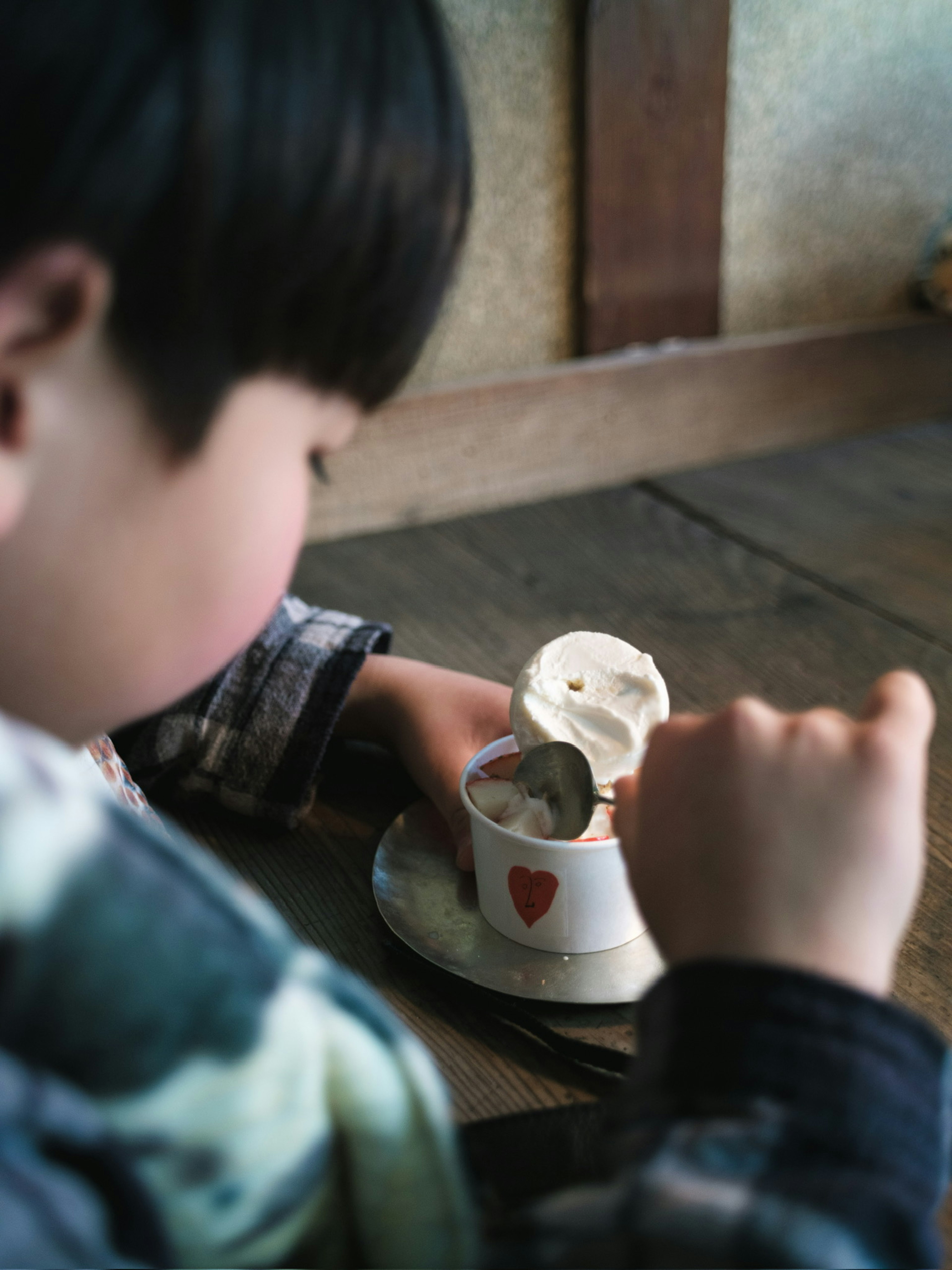 Kind genießt Eis aus einer Tasse mit Herzmuster