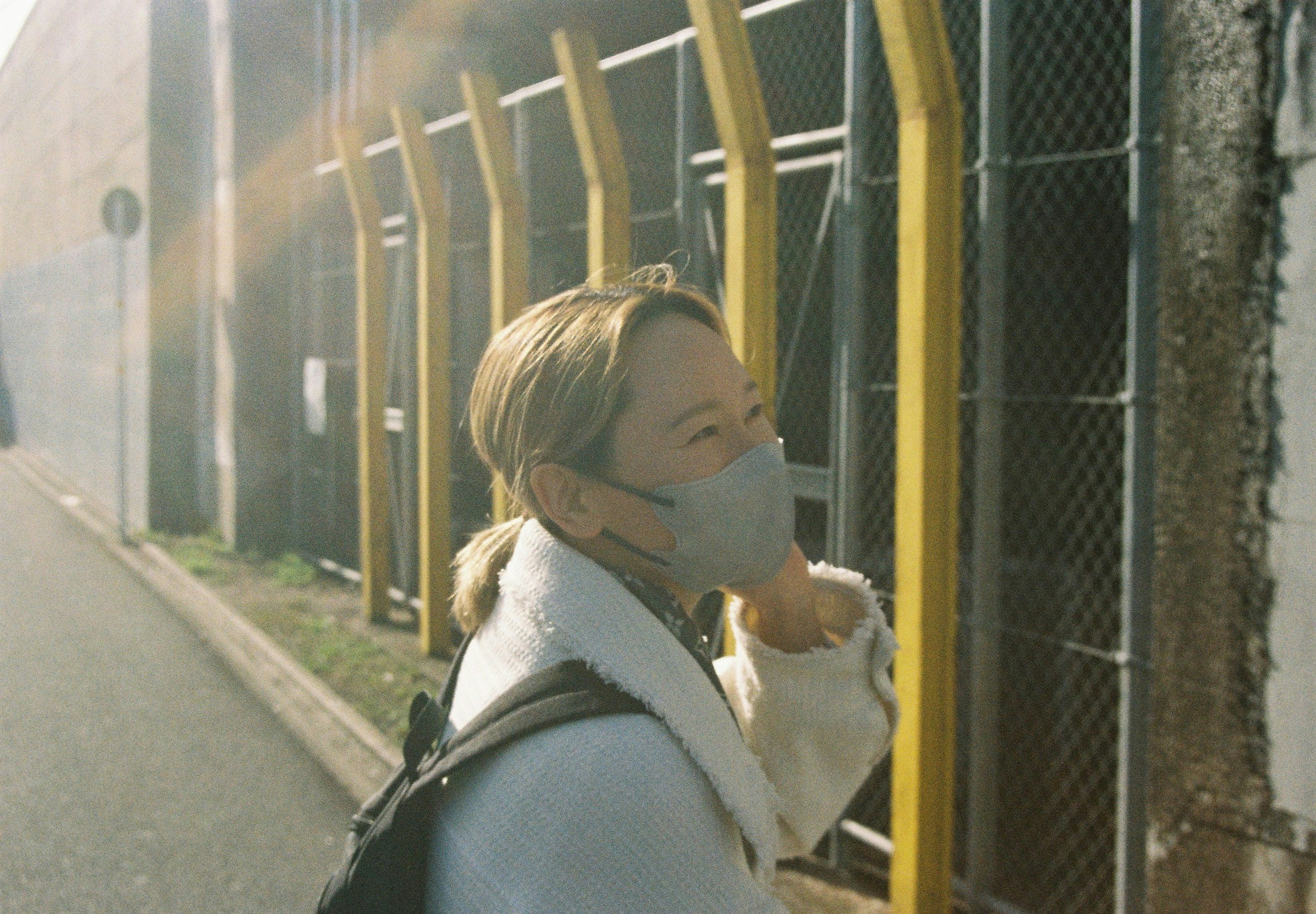 Femme portant un masque marchant devant une clôture jaune