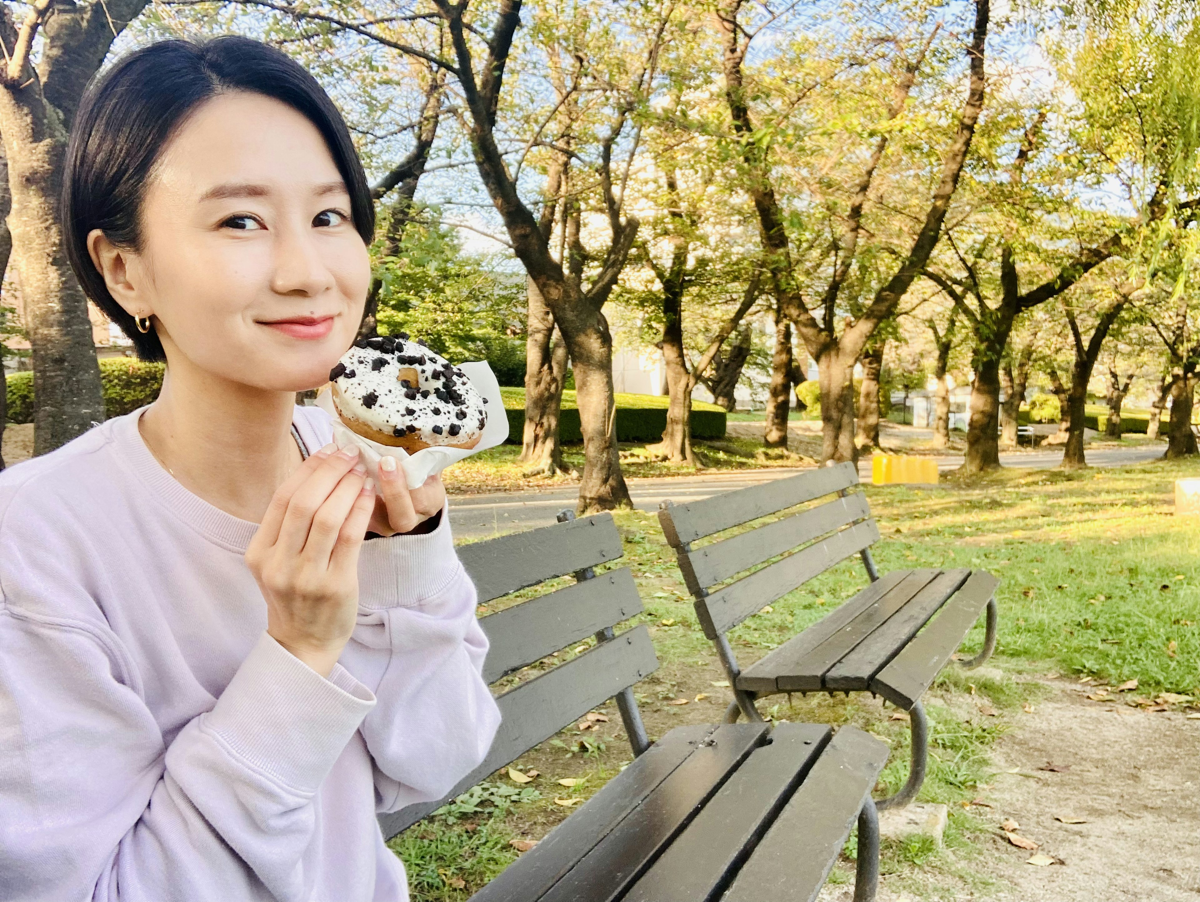 Femme souriante tenant un dessert dans un parc