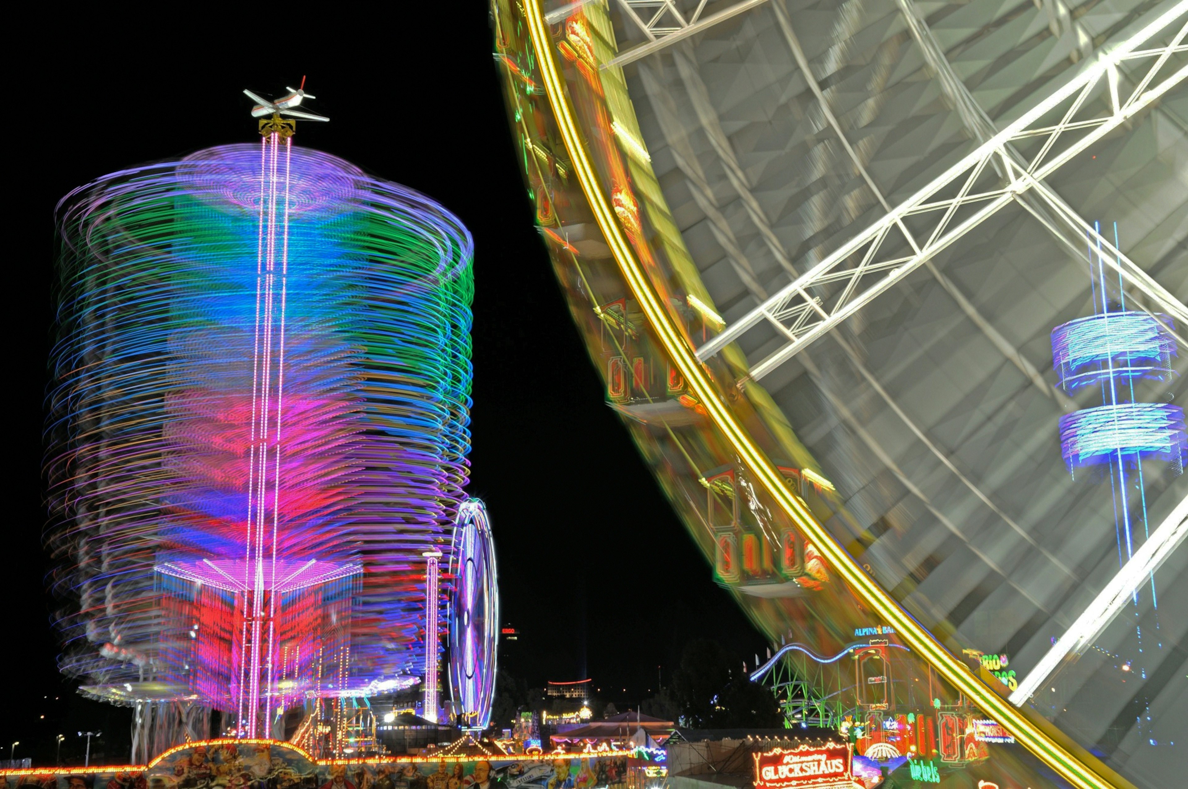 Escena nocturna con una torre iluminada de colores y una noria