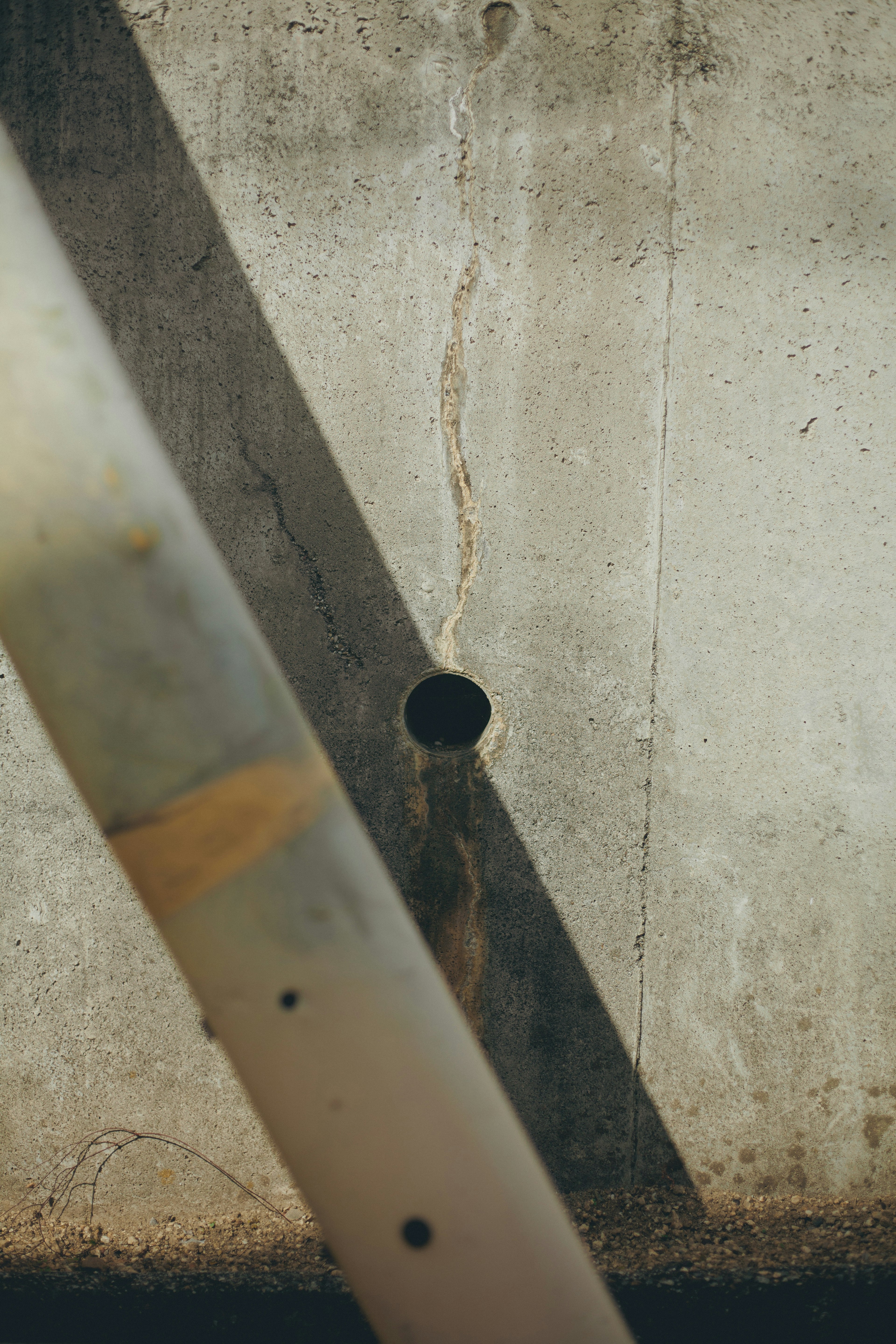 Foto di un muro di cemento con un buco e un elemento strutturale