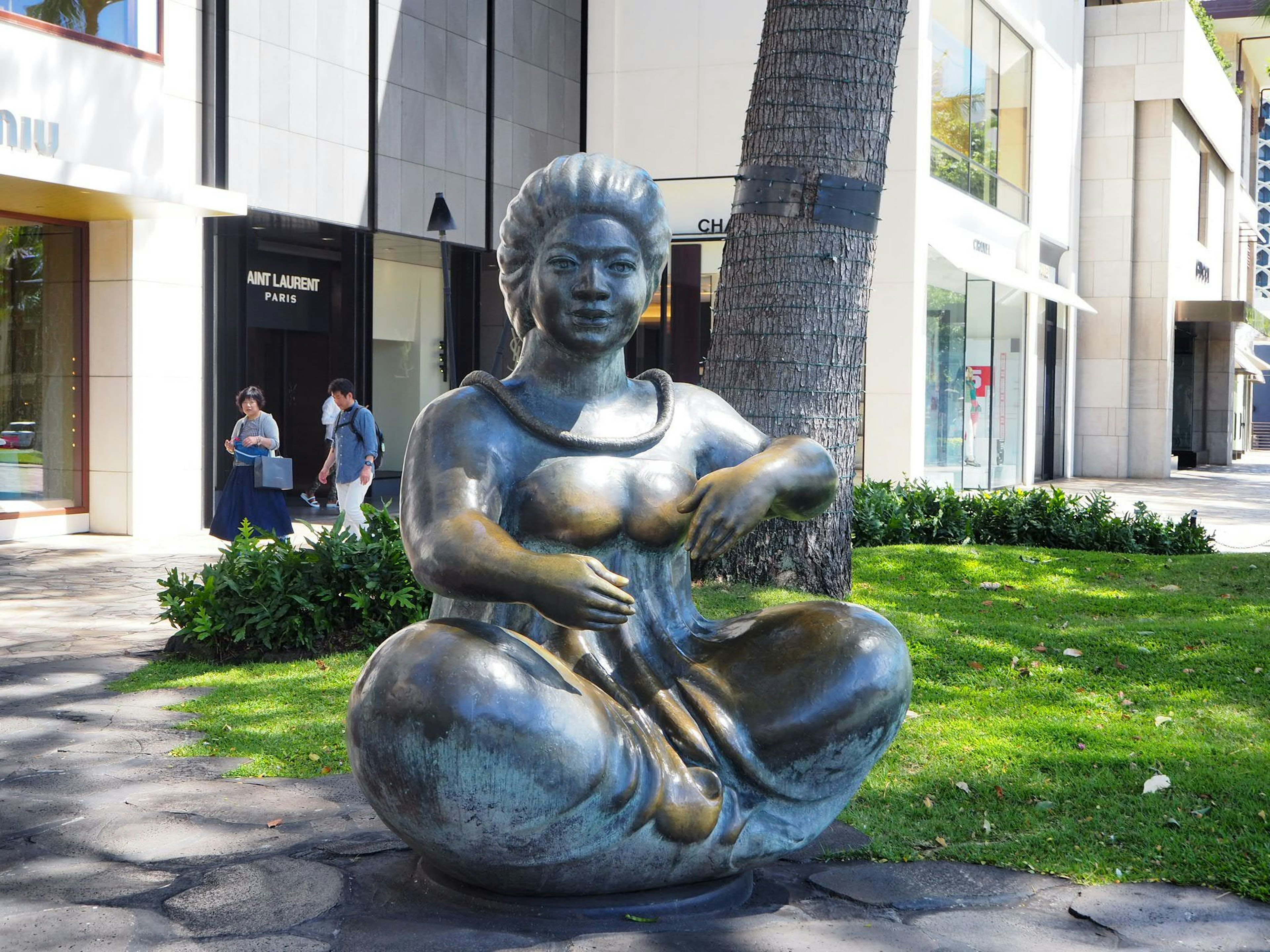 Bronze sculpture of a seated woman in a park