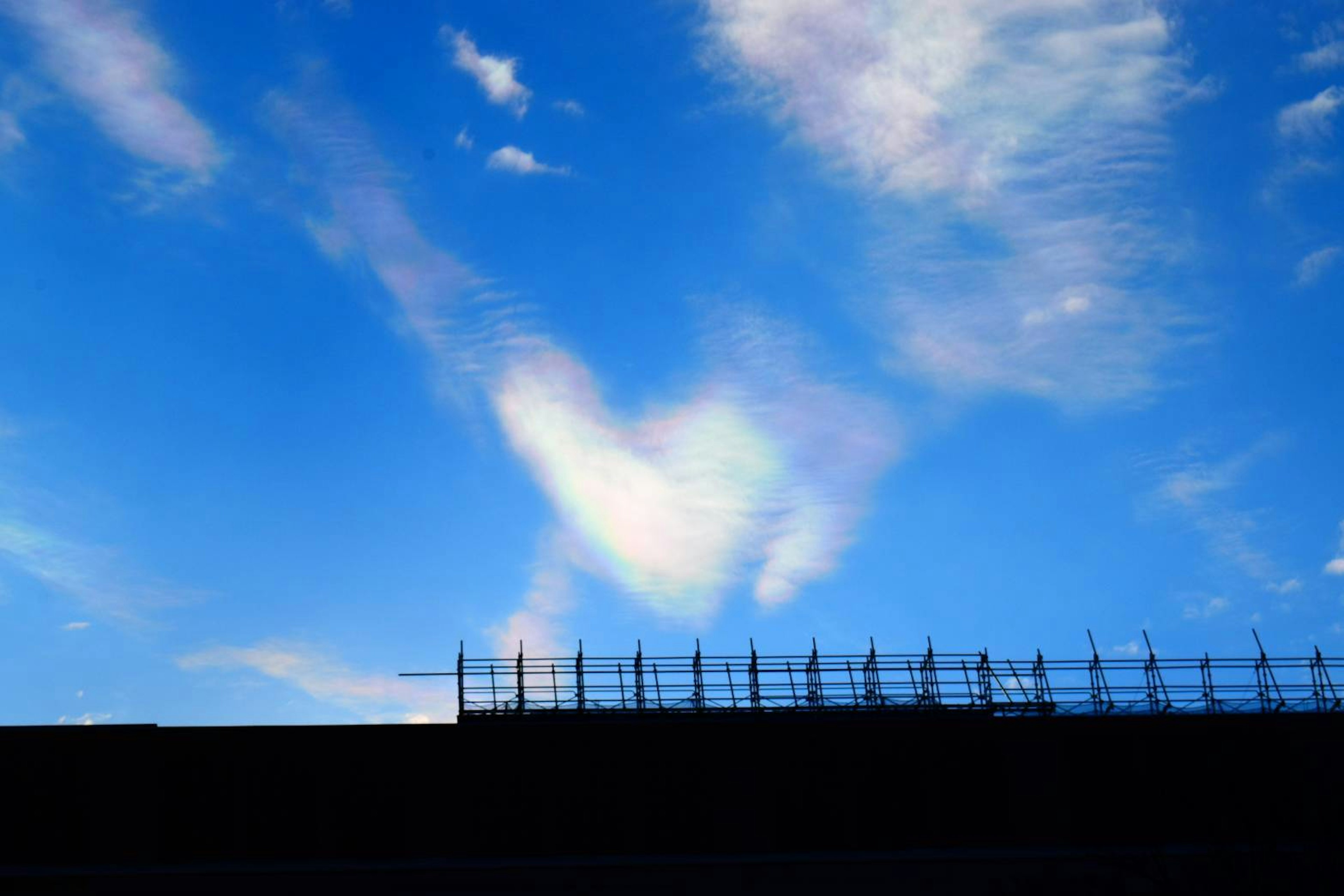 Awan berbentuk hati di langit biru dengan siluet bangunan