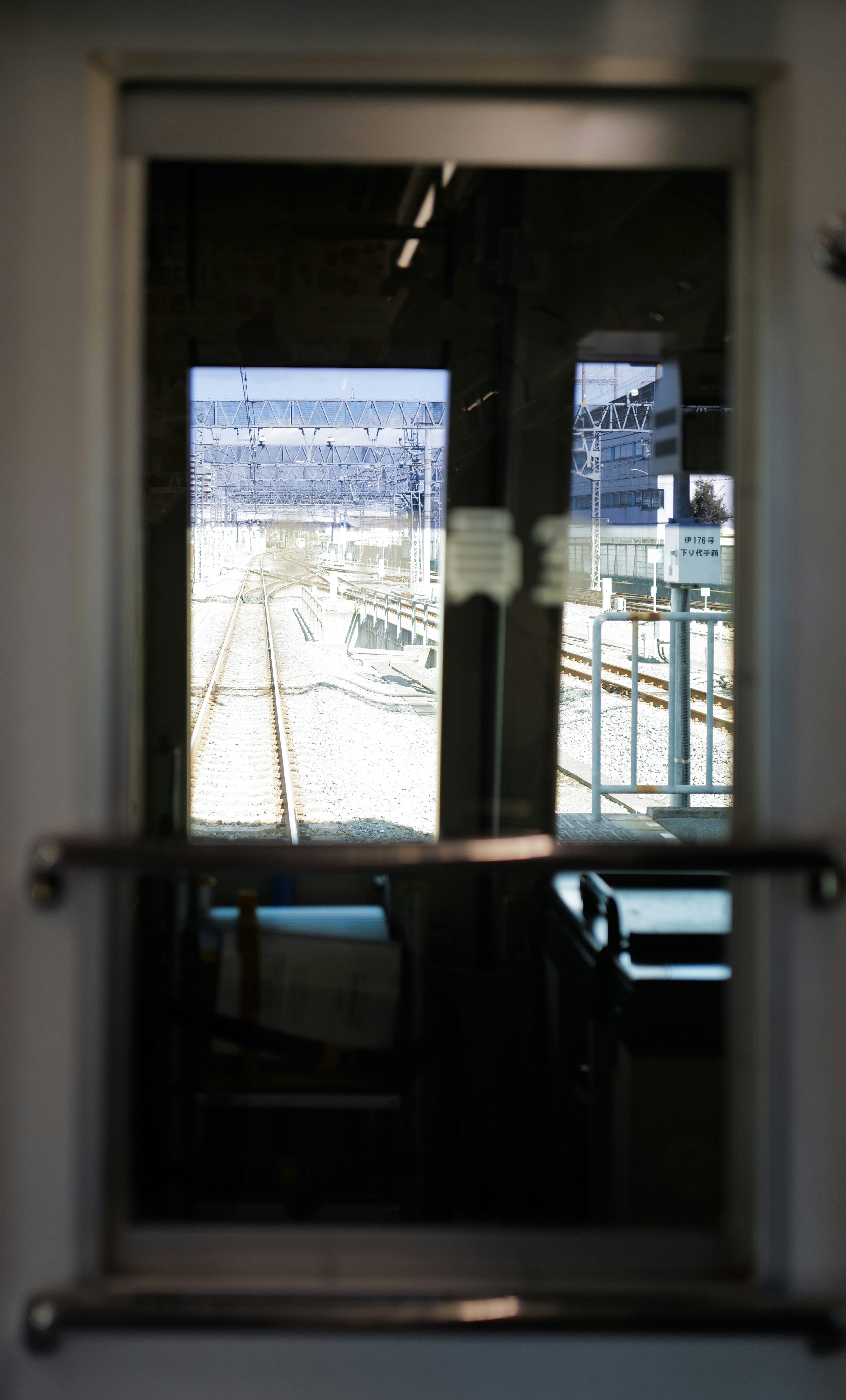 View through a train window showing a station and railway tracks