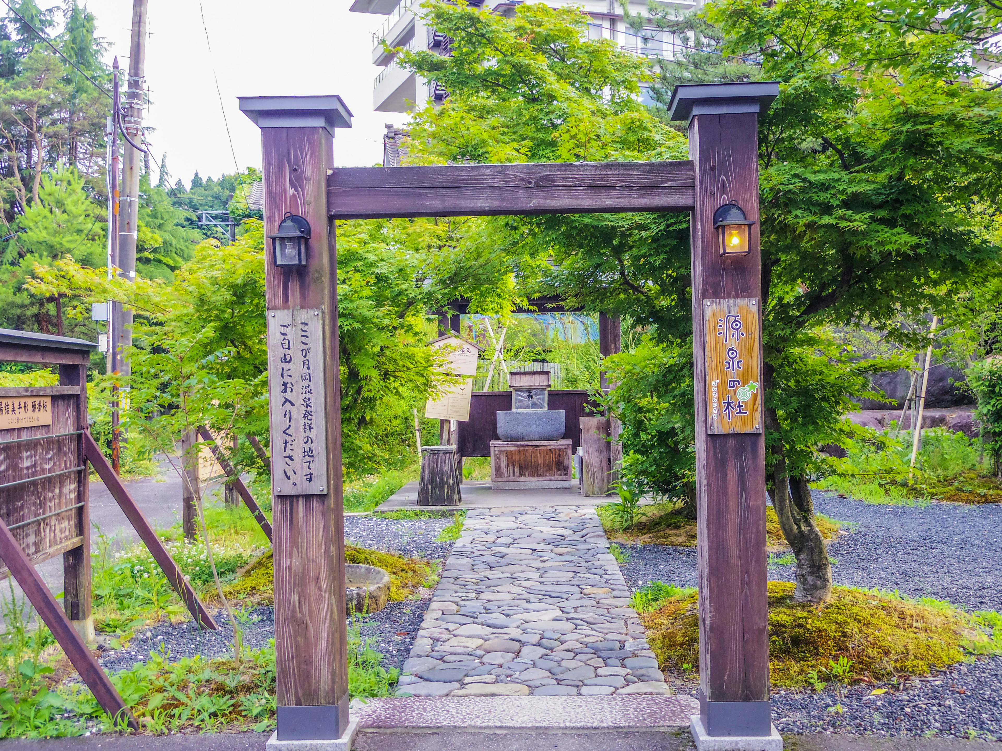 Entrance of a Japanese garden featuring a wooden gate and a stone path