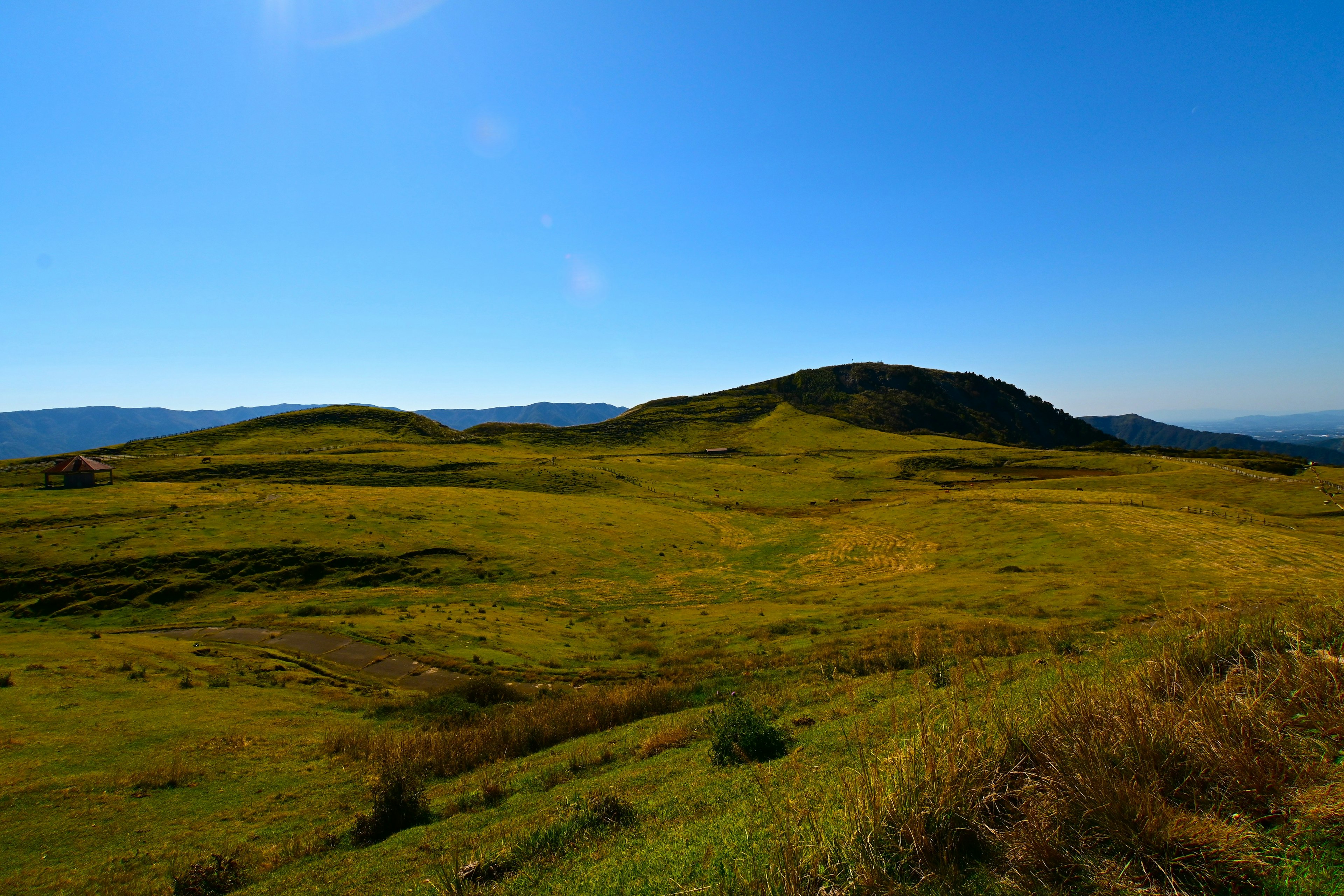 Vast green hills and a grassy landscape under a clear blue sky