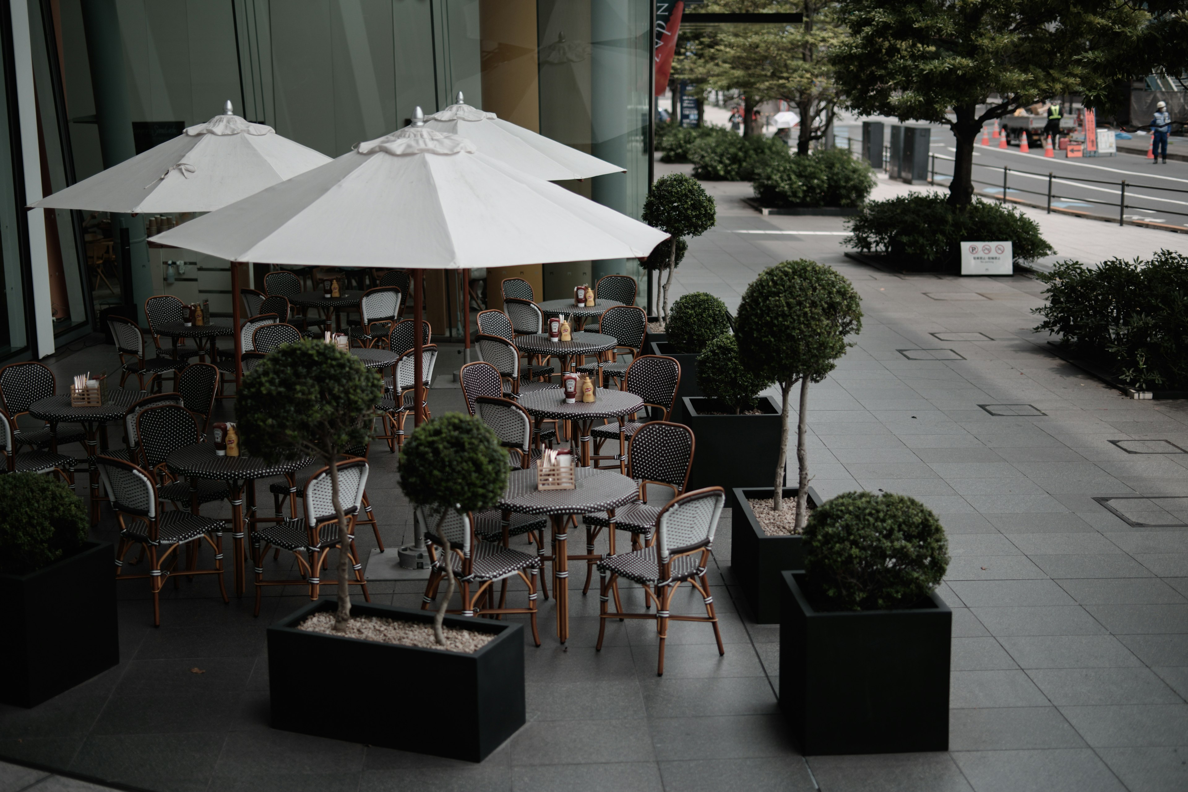 Outdoor cafe terrace with tables and chairs under white umbrellas