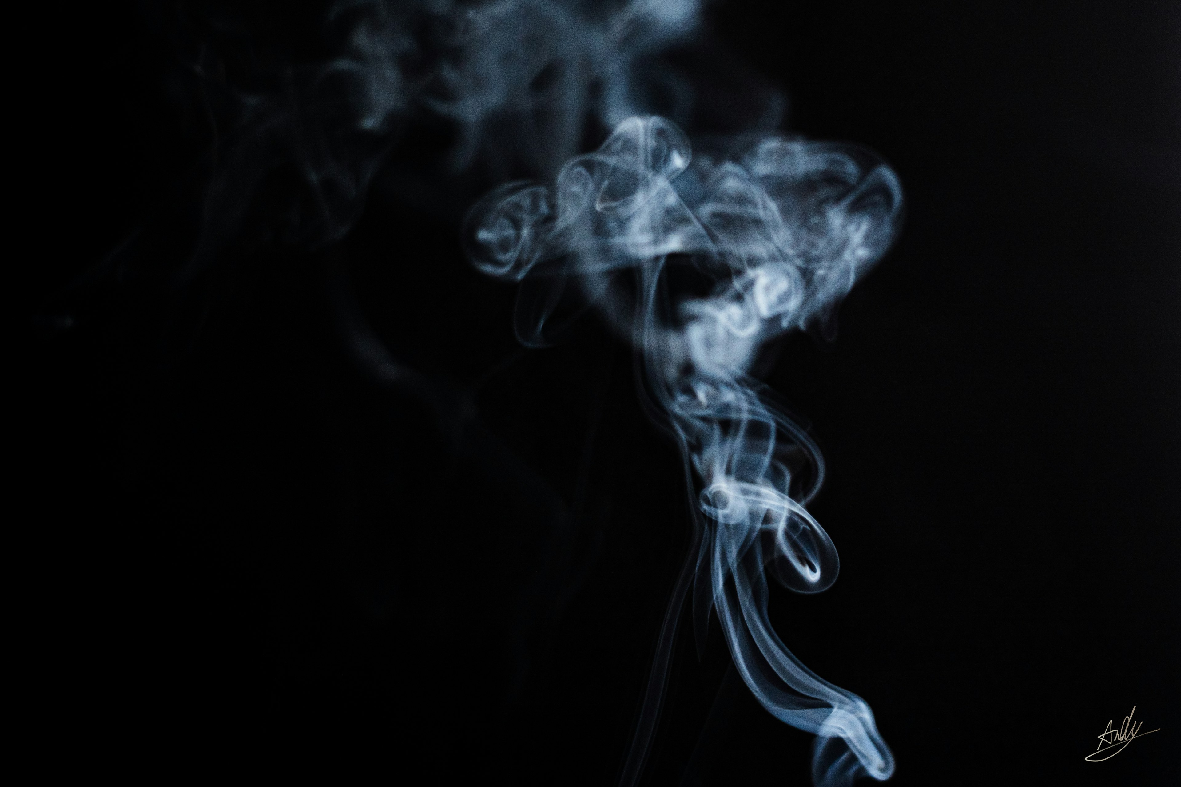 Flow of thin blue smoke on a black background