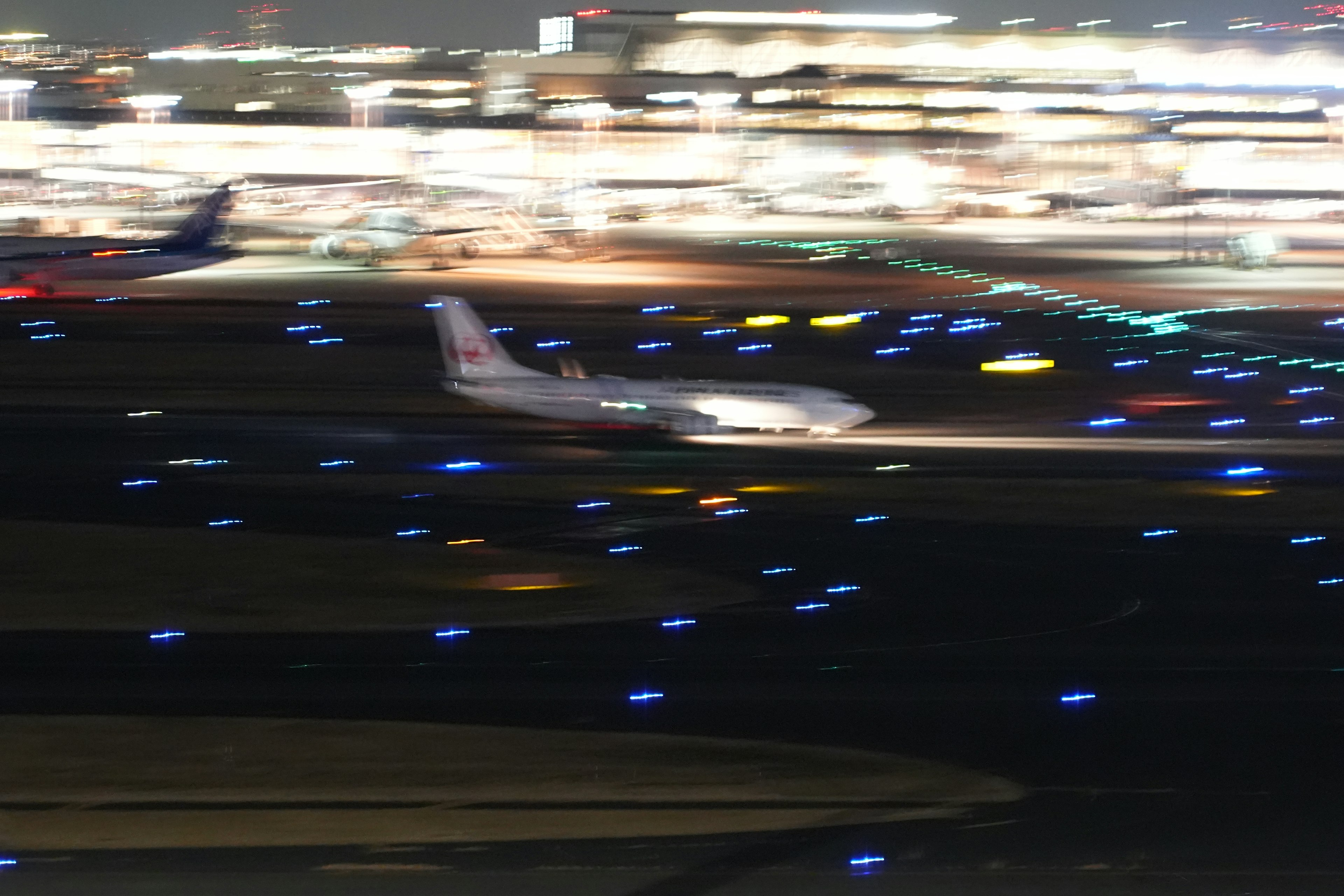 Un avión rodando en una pista iluminada por luces azules por la noche