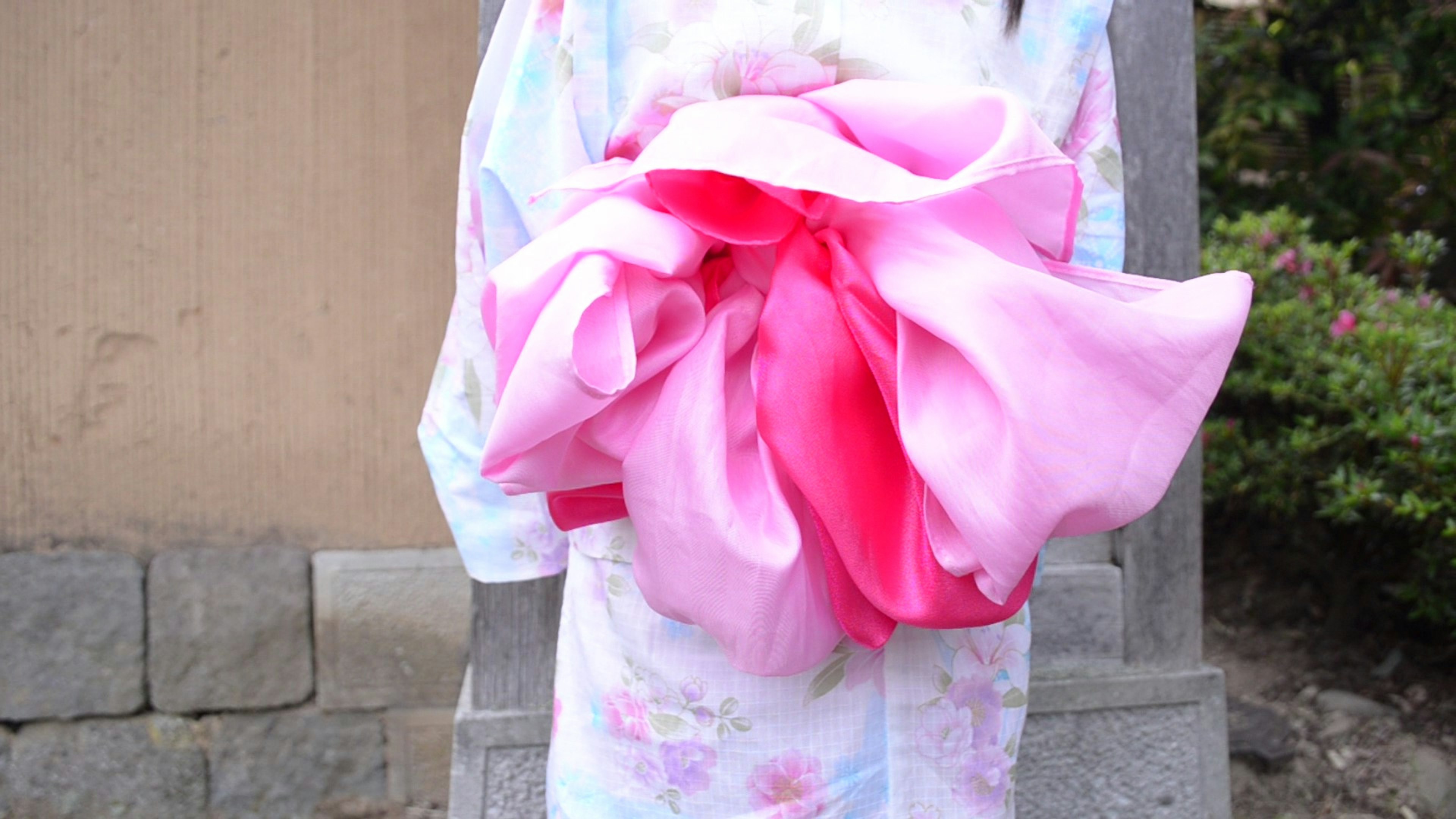 A woman in a kimono holding a large pink obi