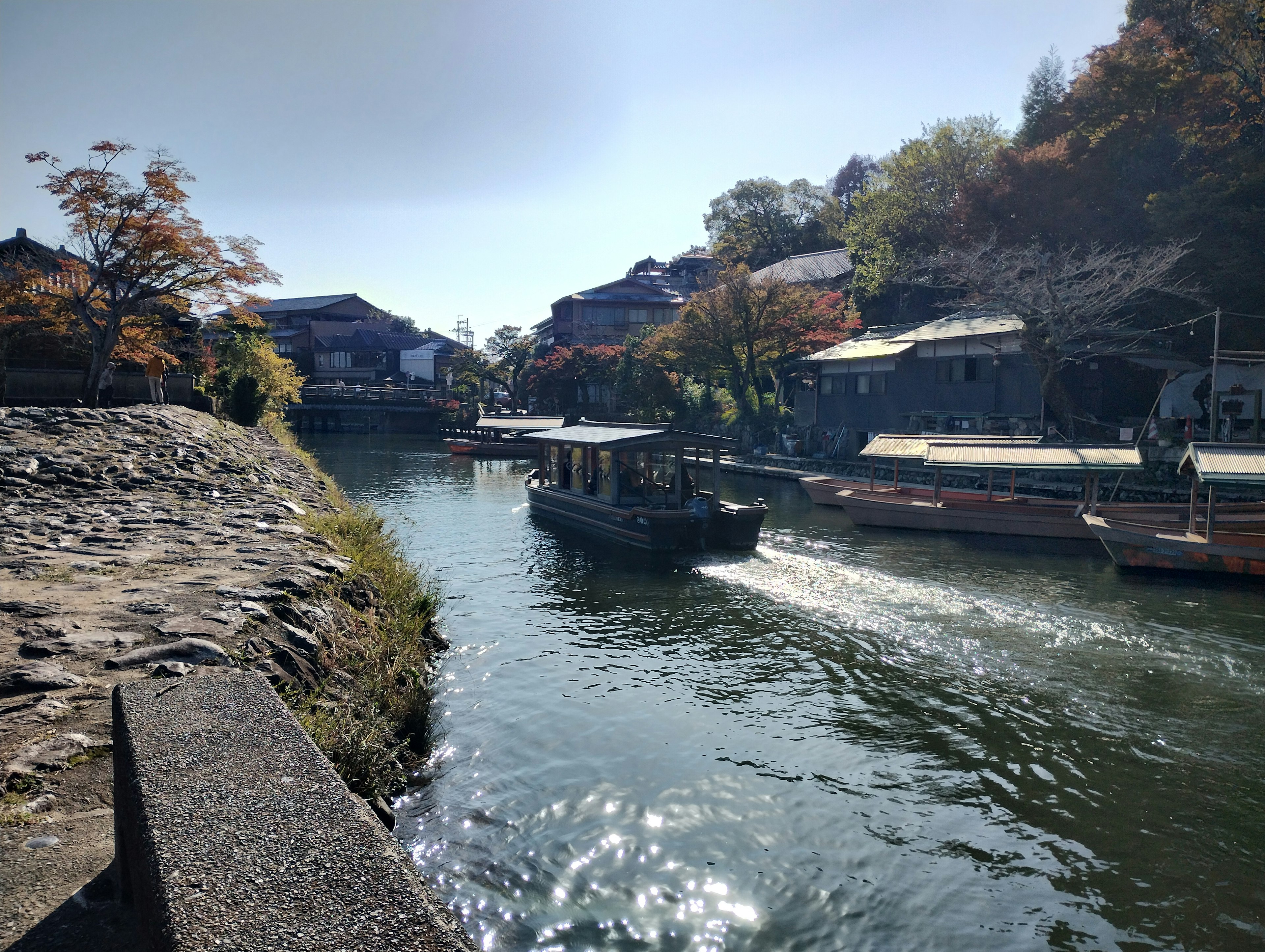 静かな川沿いに停泊する船と周囲の家々の風景