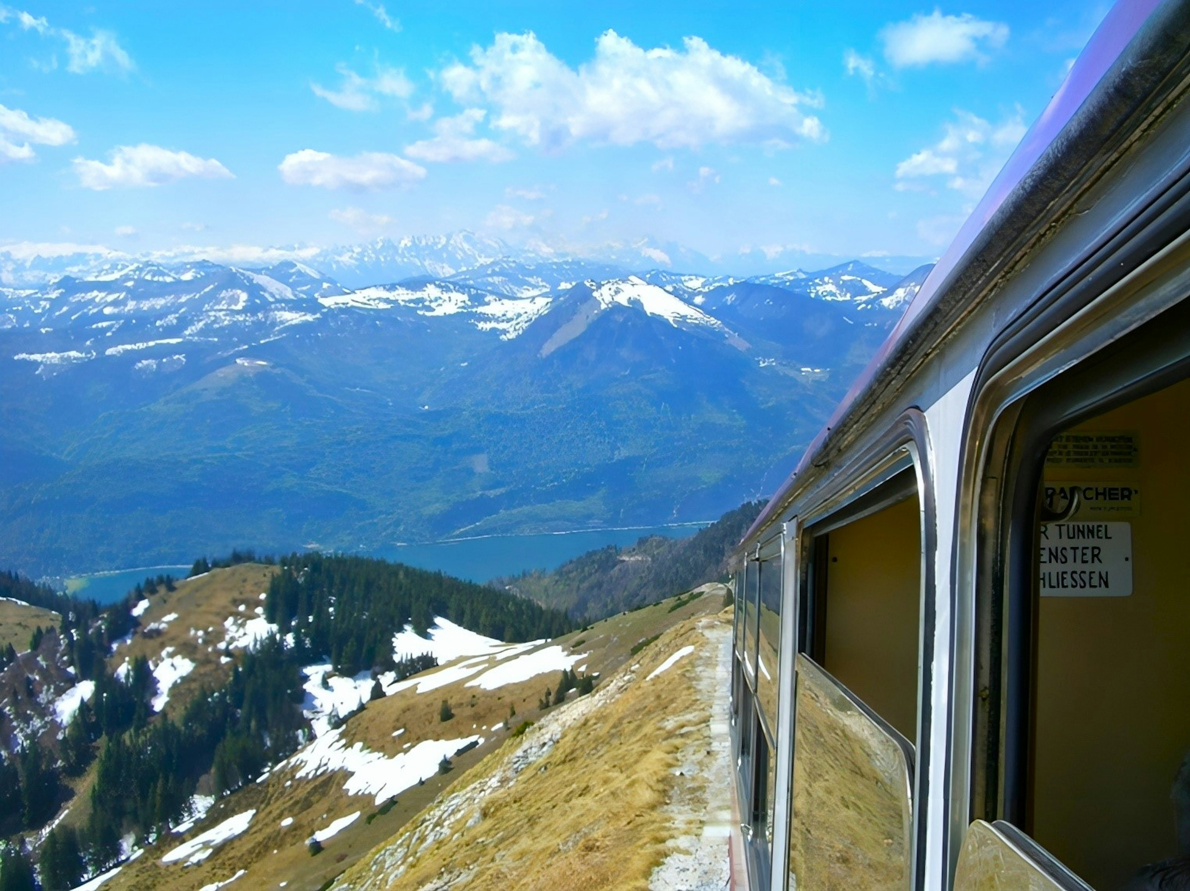 Blick aus dem Zugfenster auf Berge und blauen Himmel