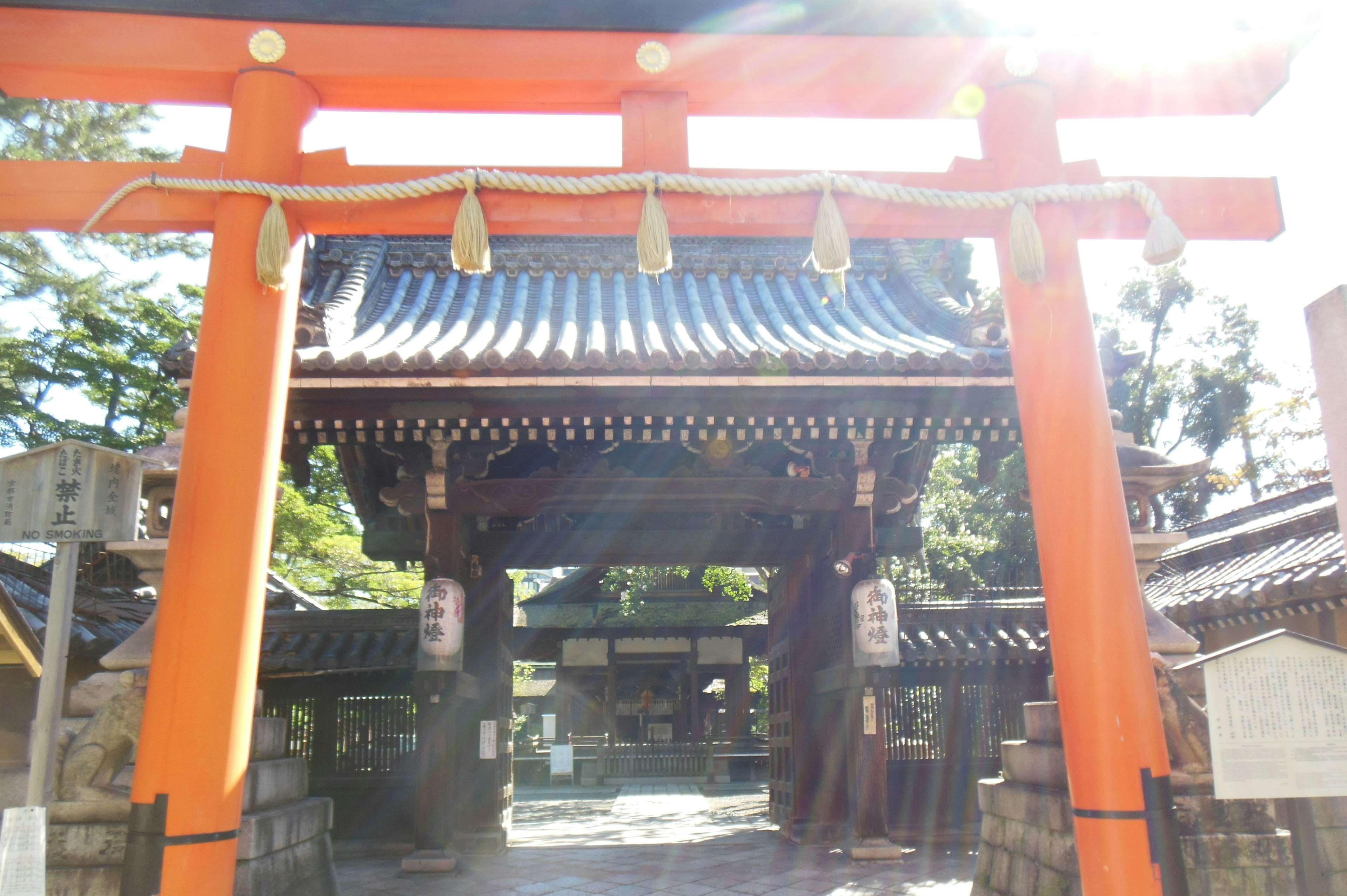 Oranger Torii mit traditioneller japanischer Architektur im Hintergrund