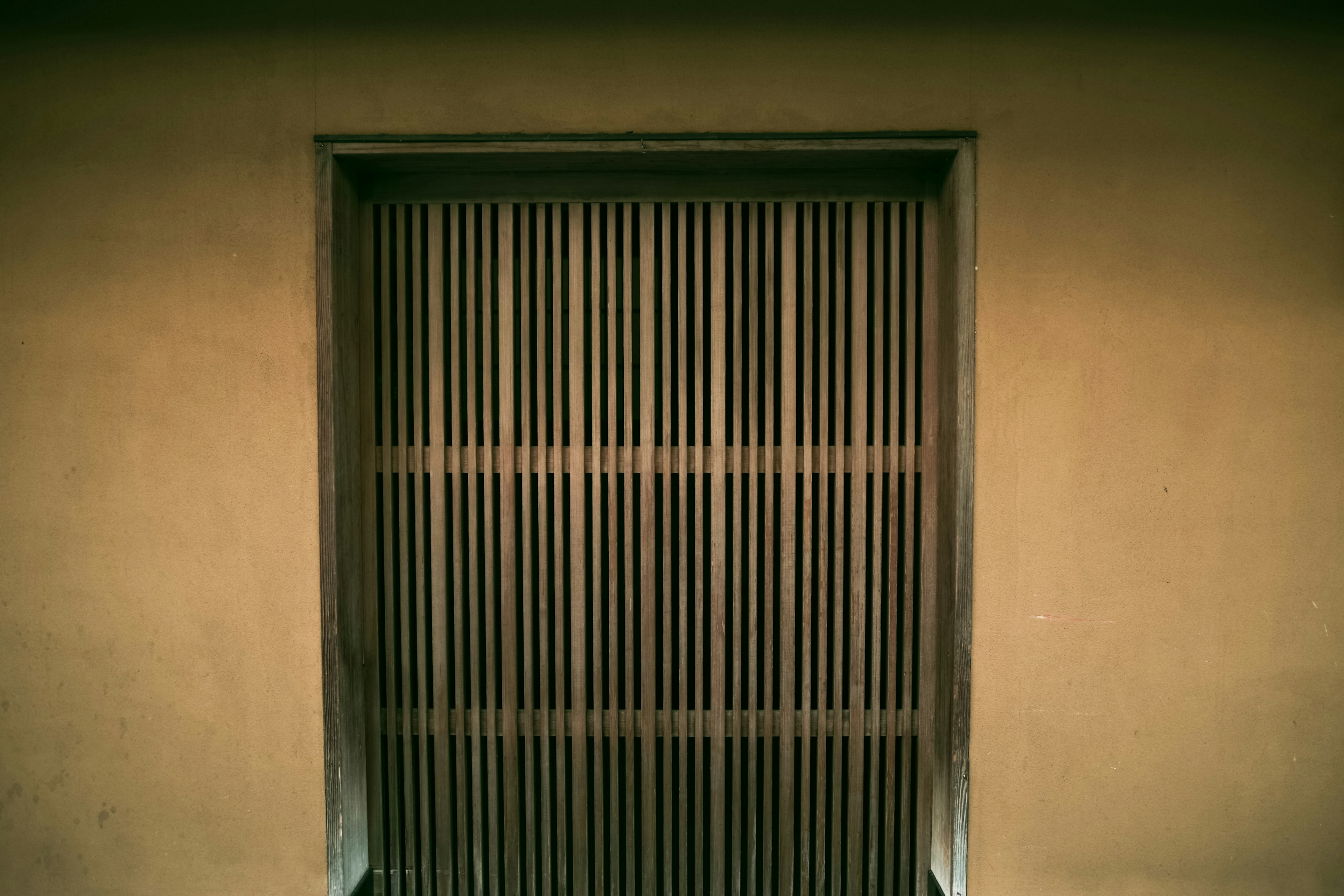 Metal door with vertical slits and surrounding wall