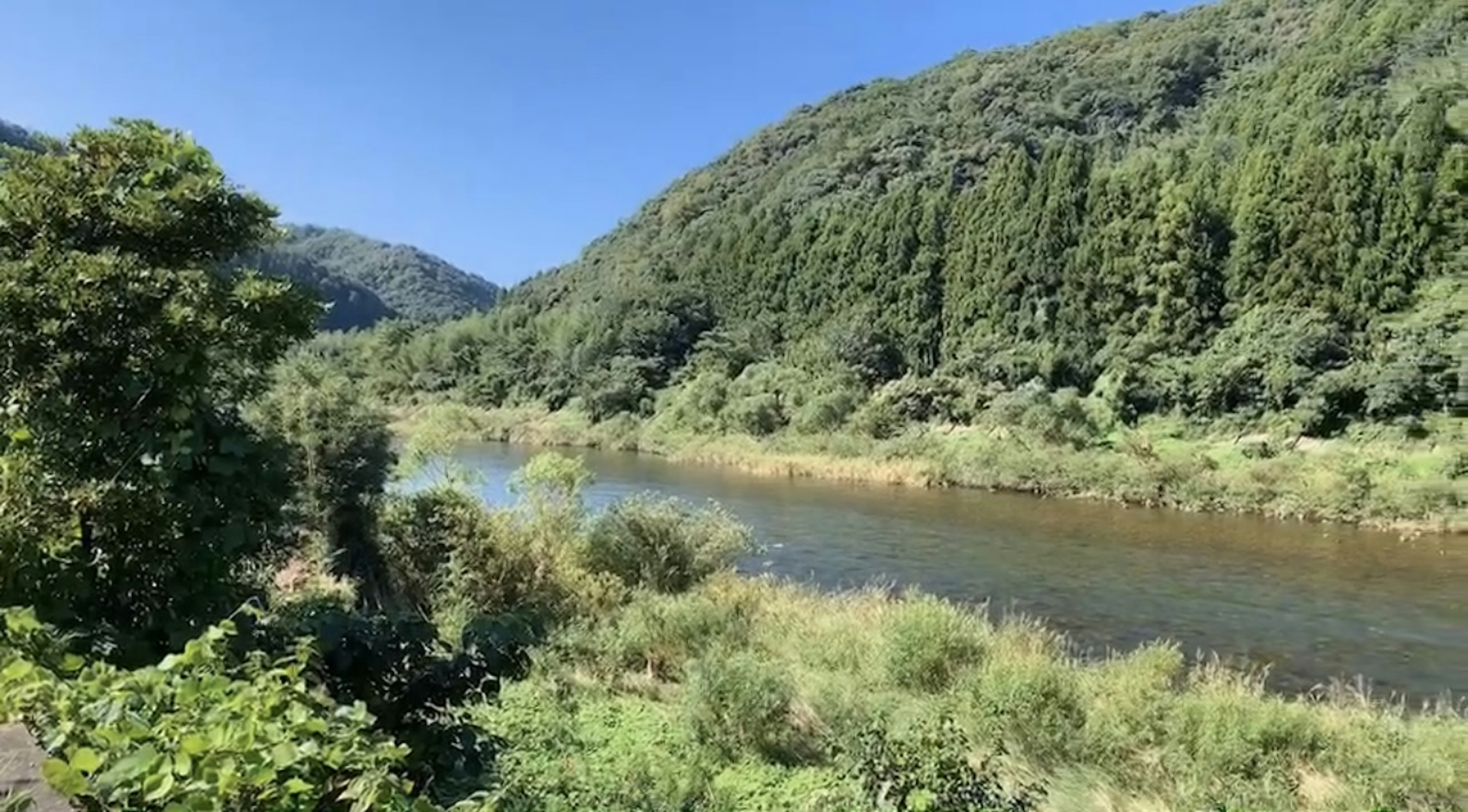 寧靜的河流風景，周圍環繞著郁郁蔥蔥的山脈