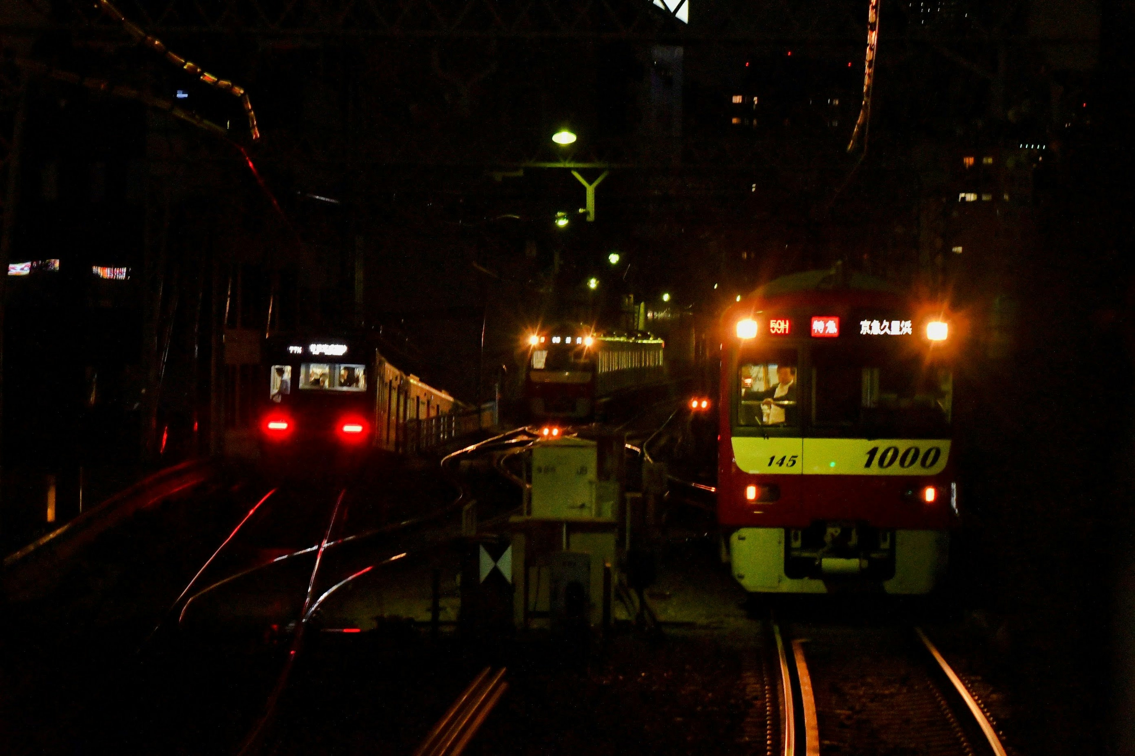 Kendaraan kerja dan kereta yang diterangi di stasiun kereta api saat malam