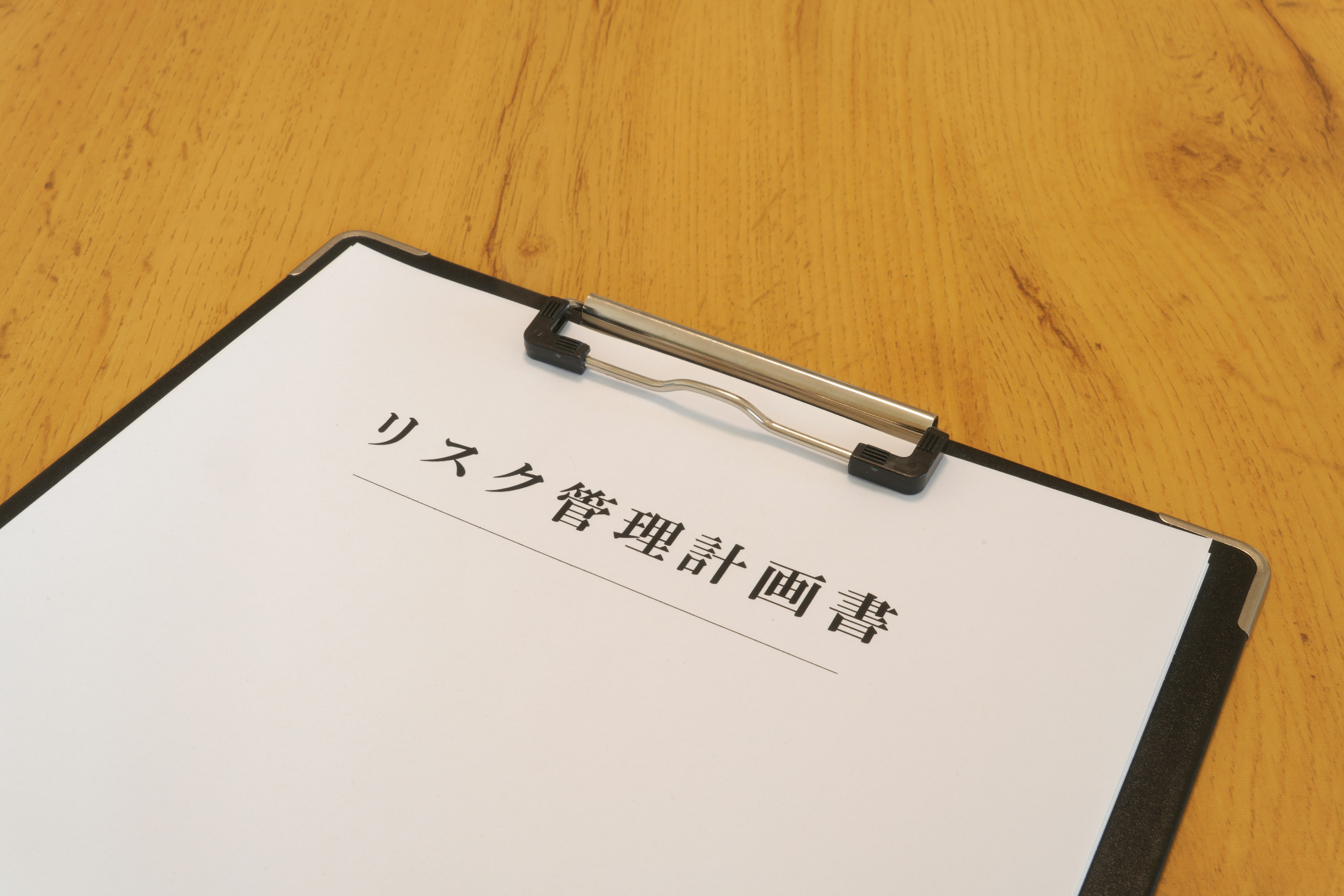 Clipboard with risk management plan document on wooden table