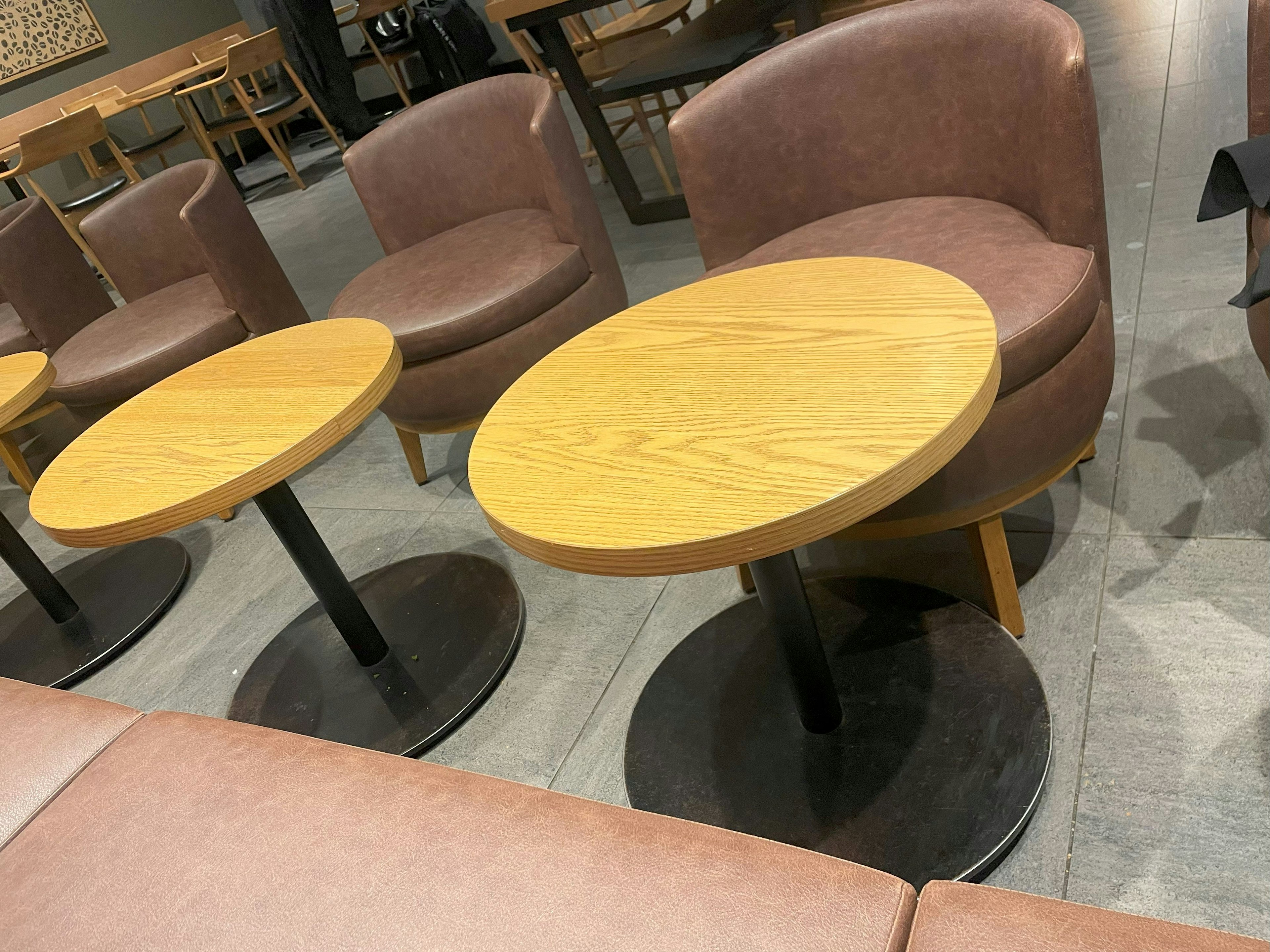 Round wooden tables and leather chairs in a café interior