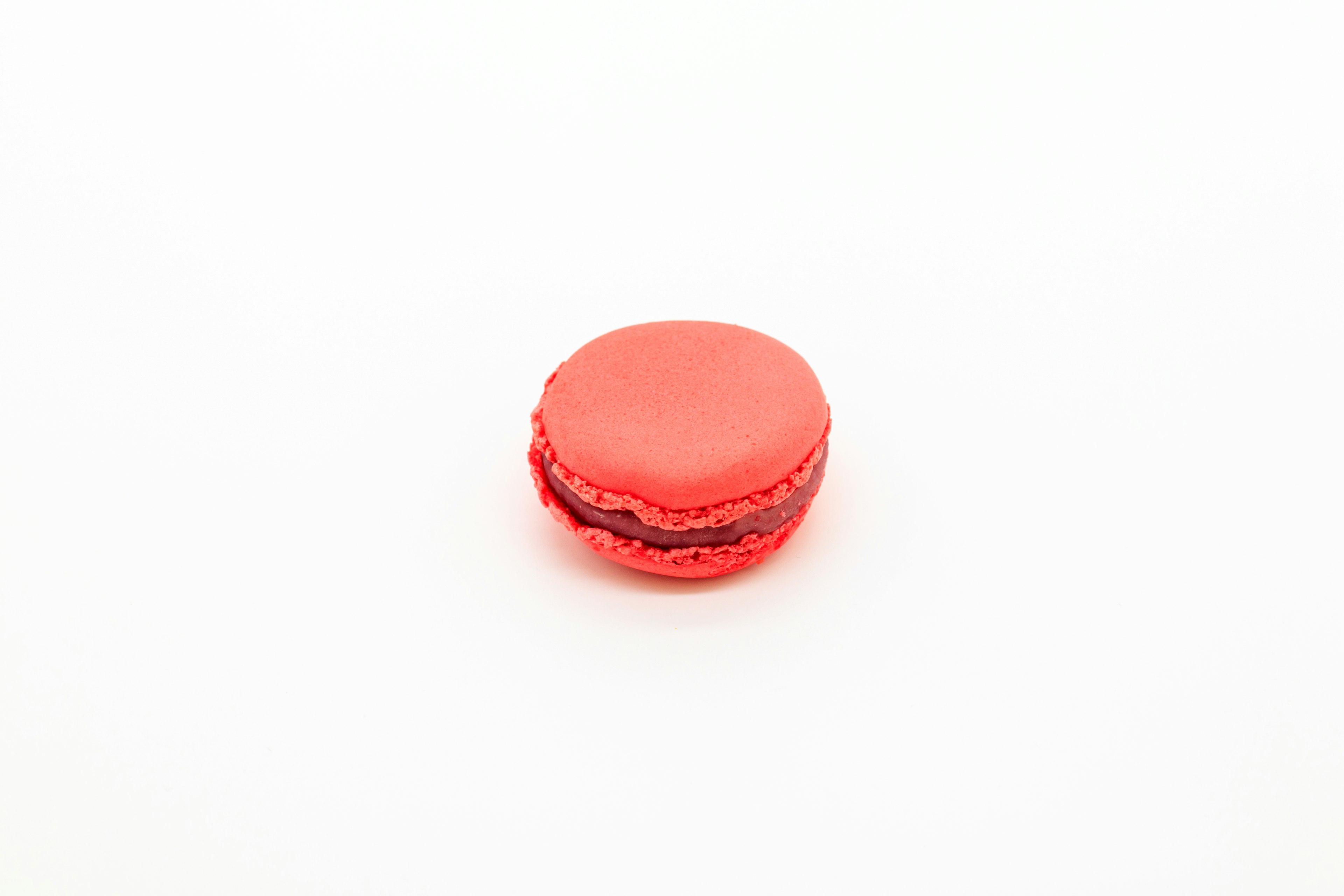 Un macaron rouge posé sur un fond blanc