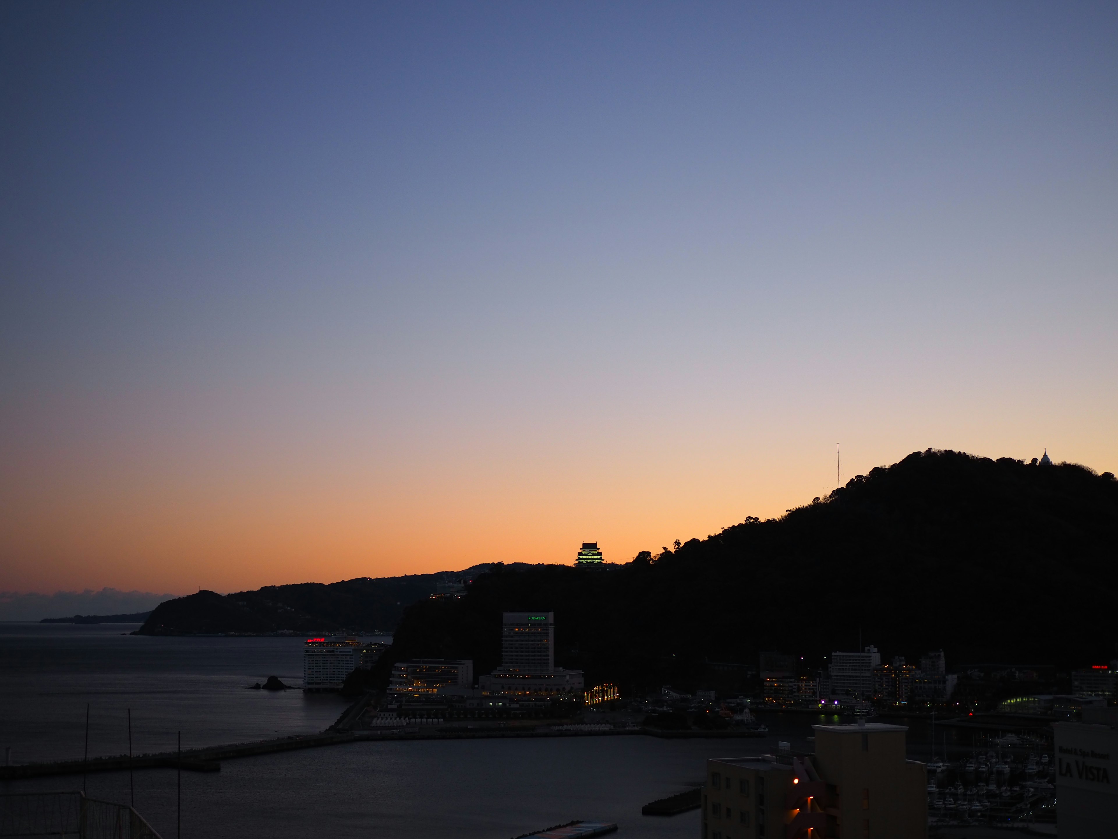 海上日落的景色，有山和城市燈光