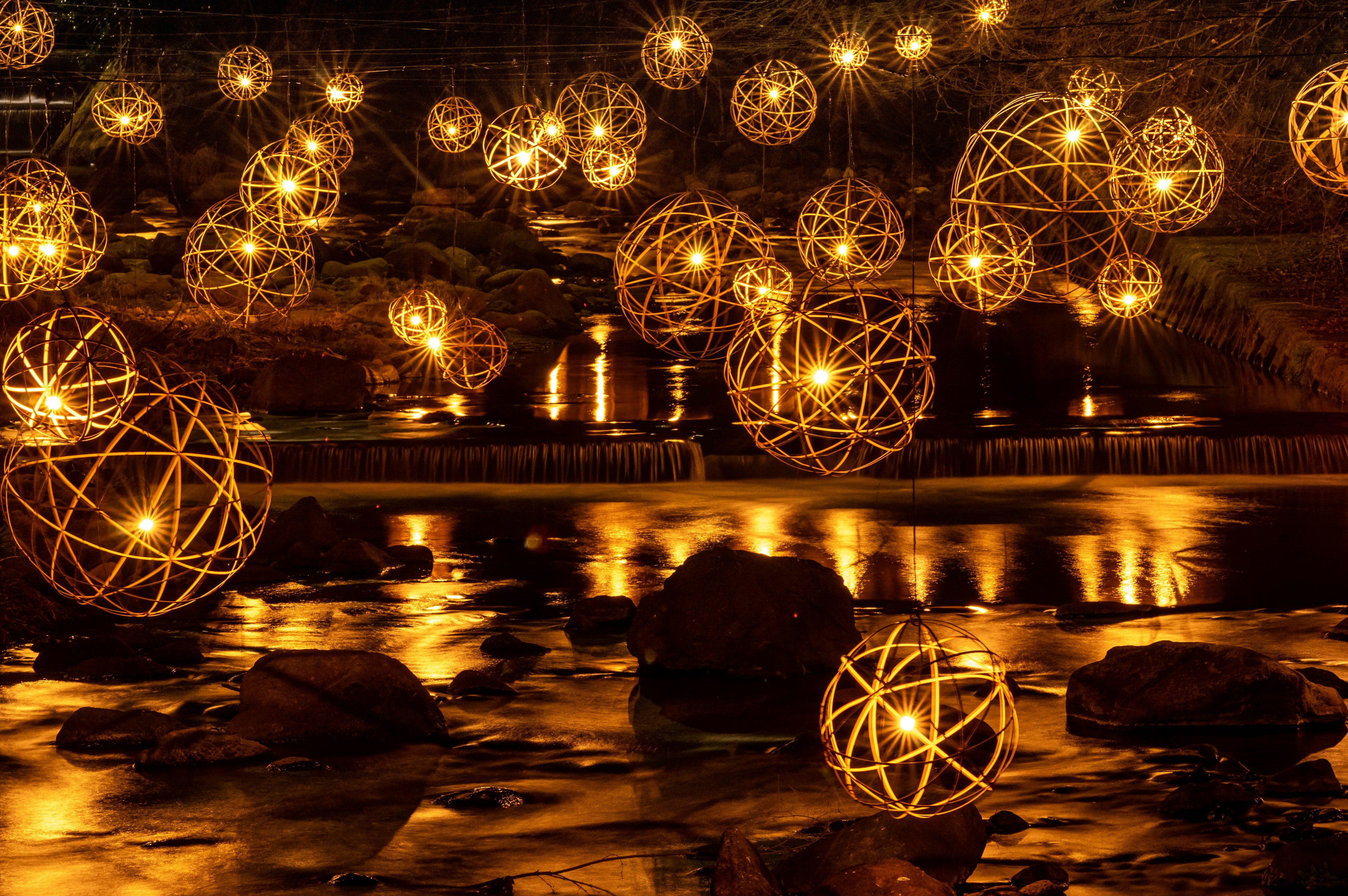 Beautiful scene of glowing decorative spheres floating on a river