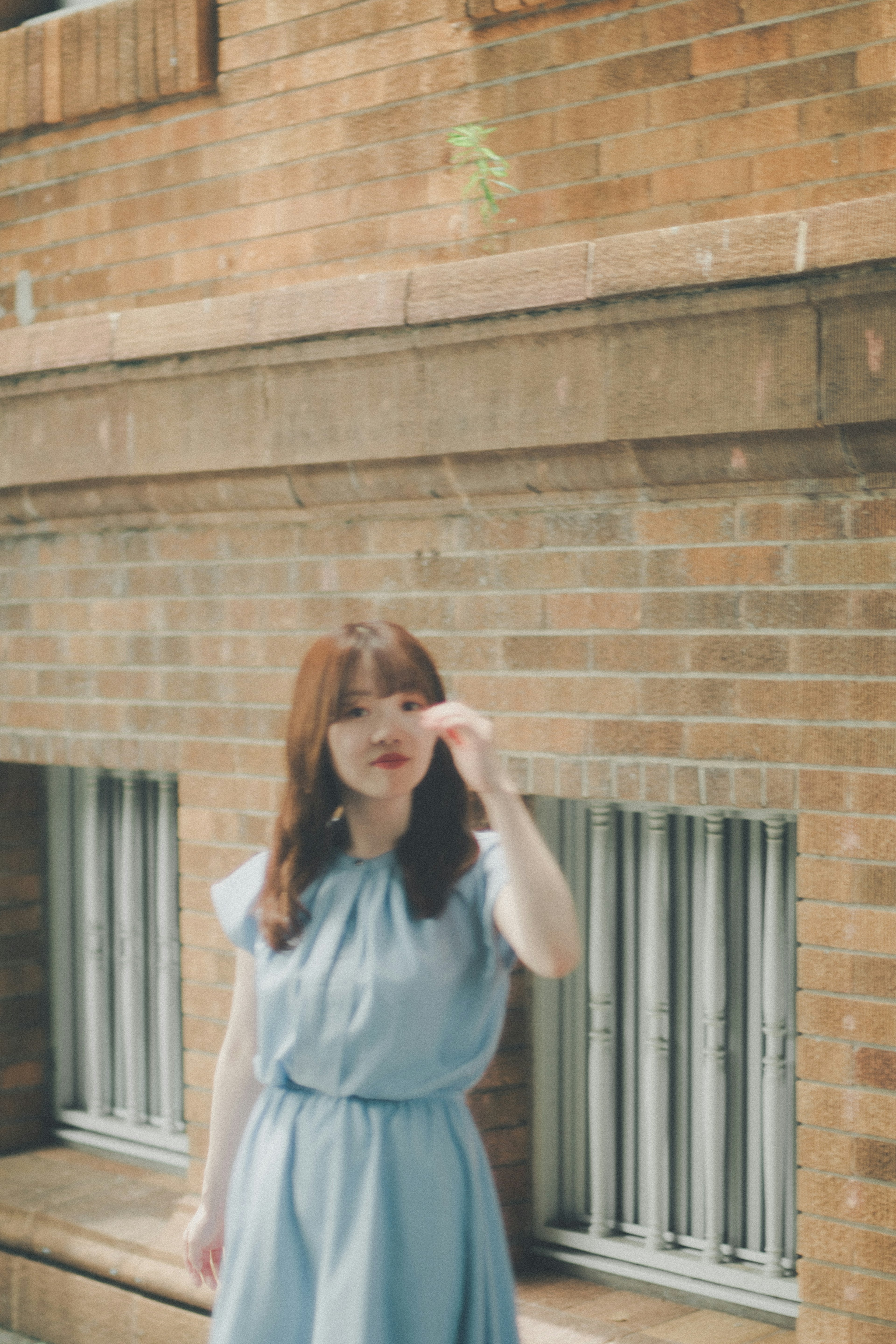 A woman in a blue dress posing in front of a brick wall