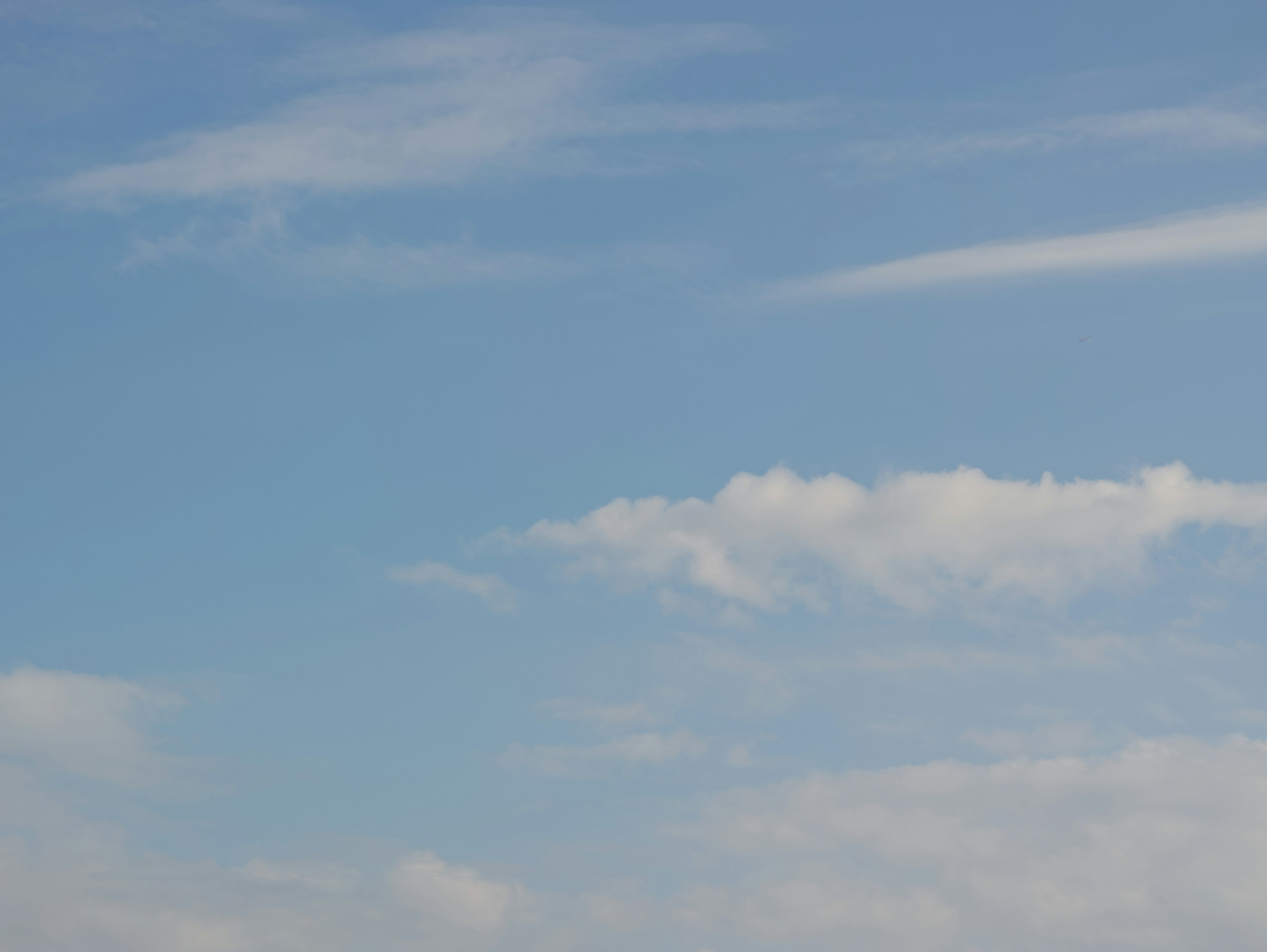 Calm blue sky with soft white clouds