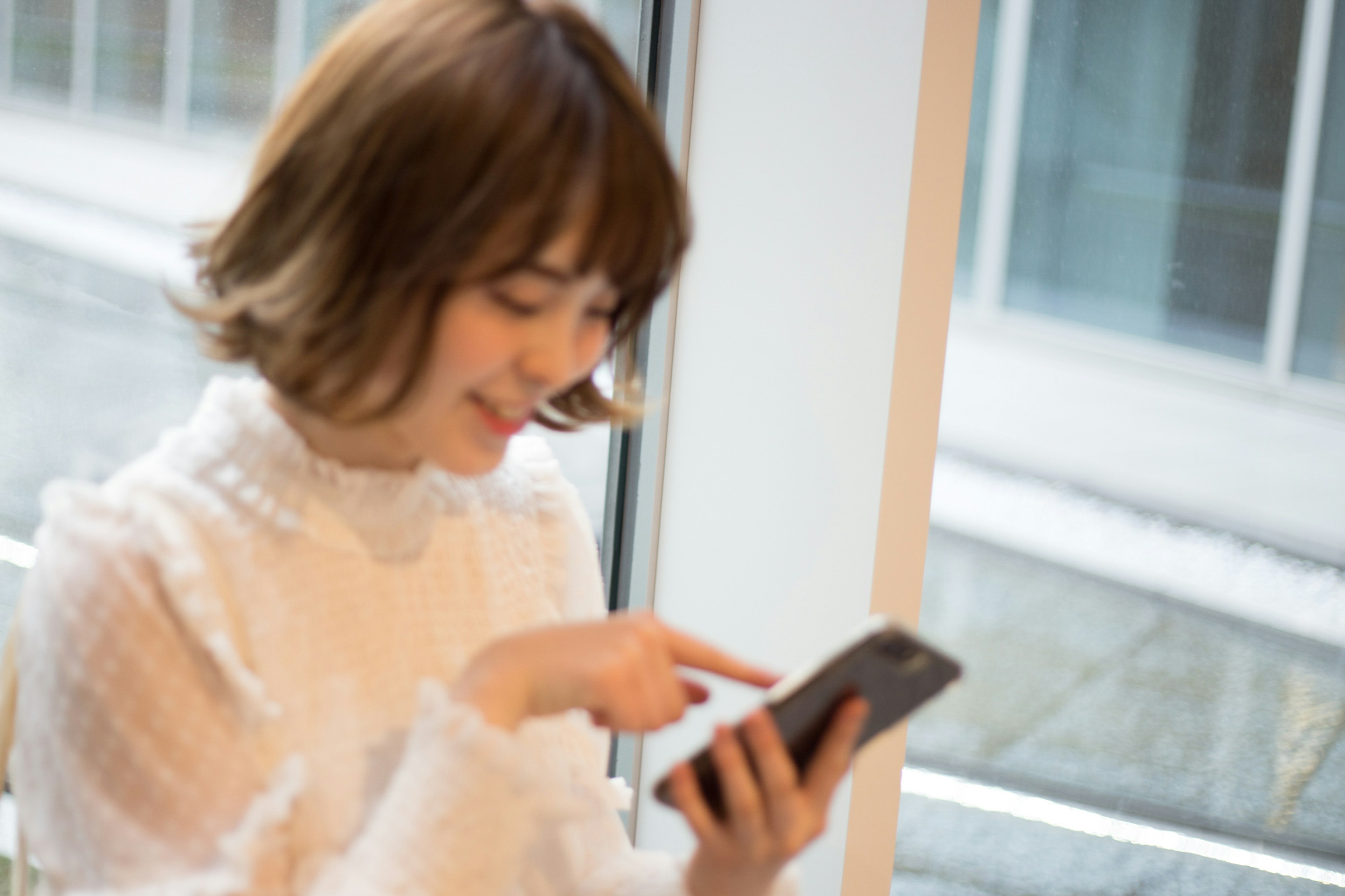 Eine Frau, die ein Smartphone am Fenster benutzt