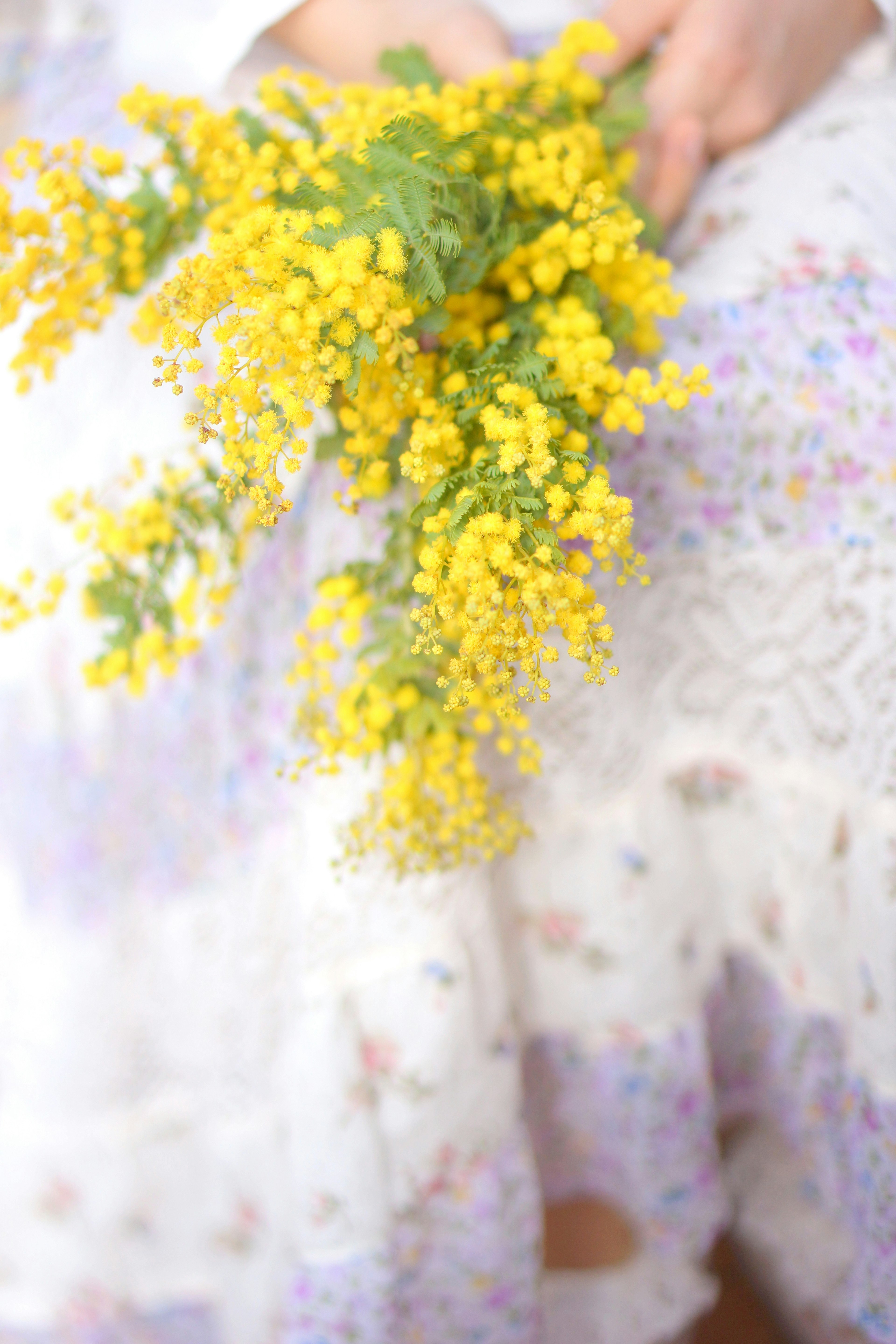 A woman holding a bouquet of yellow flowers with a floral skirt