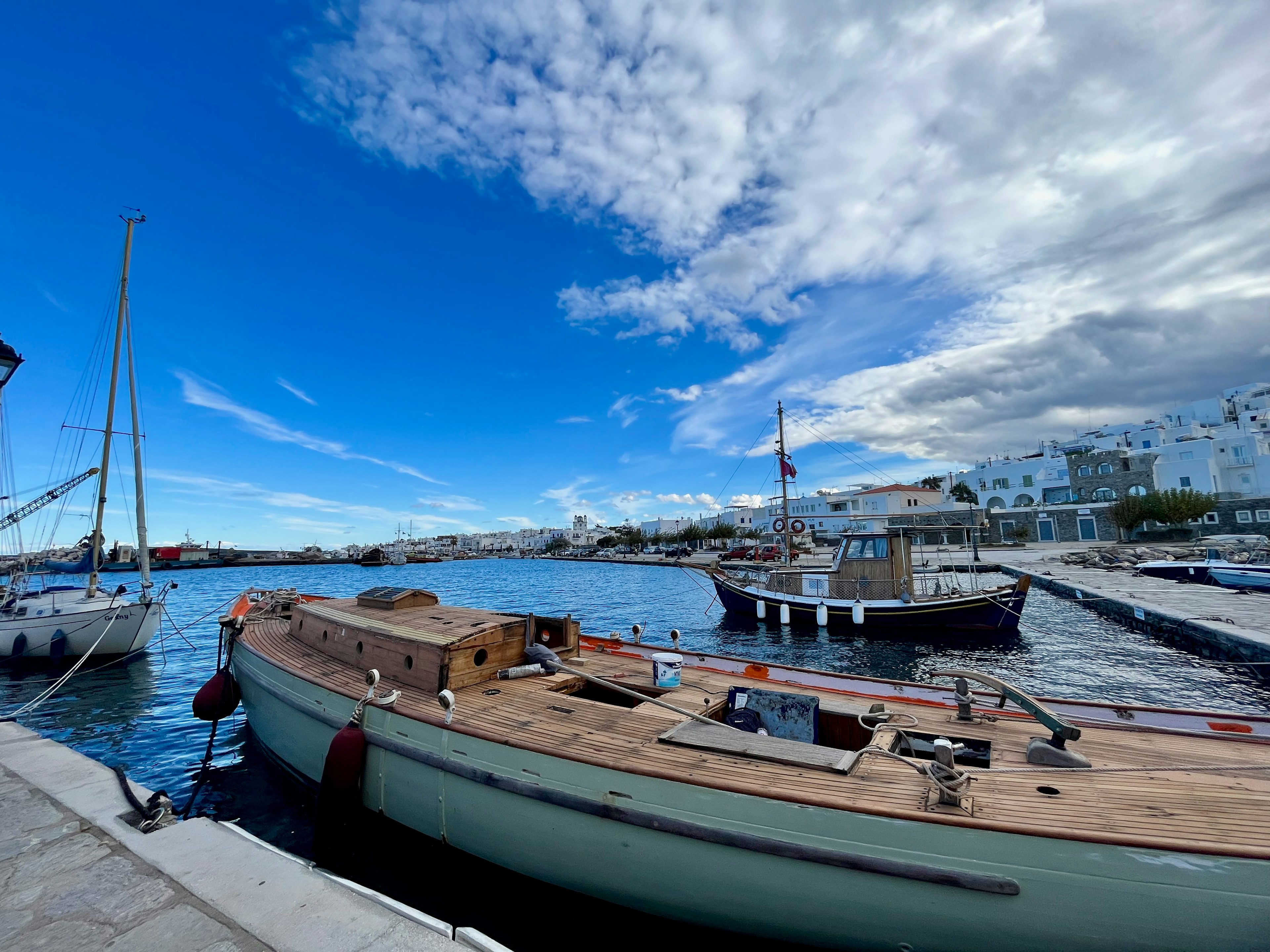 Scène de port avec des bateaux et un quai sous un ciel bleu avec des nuages