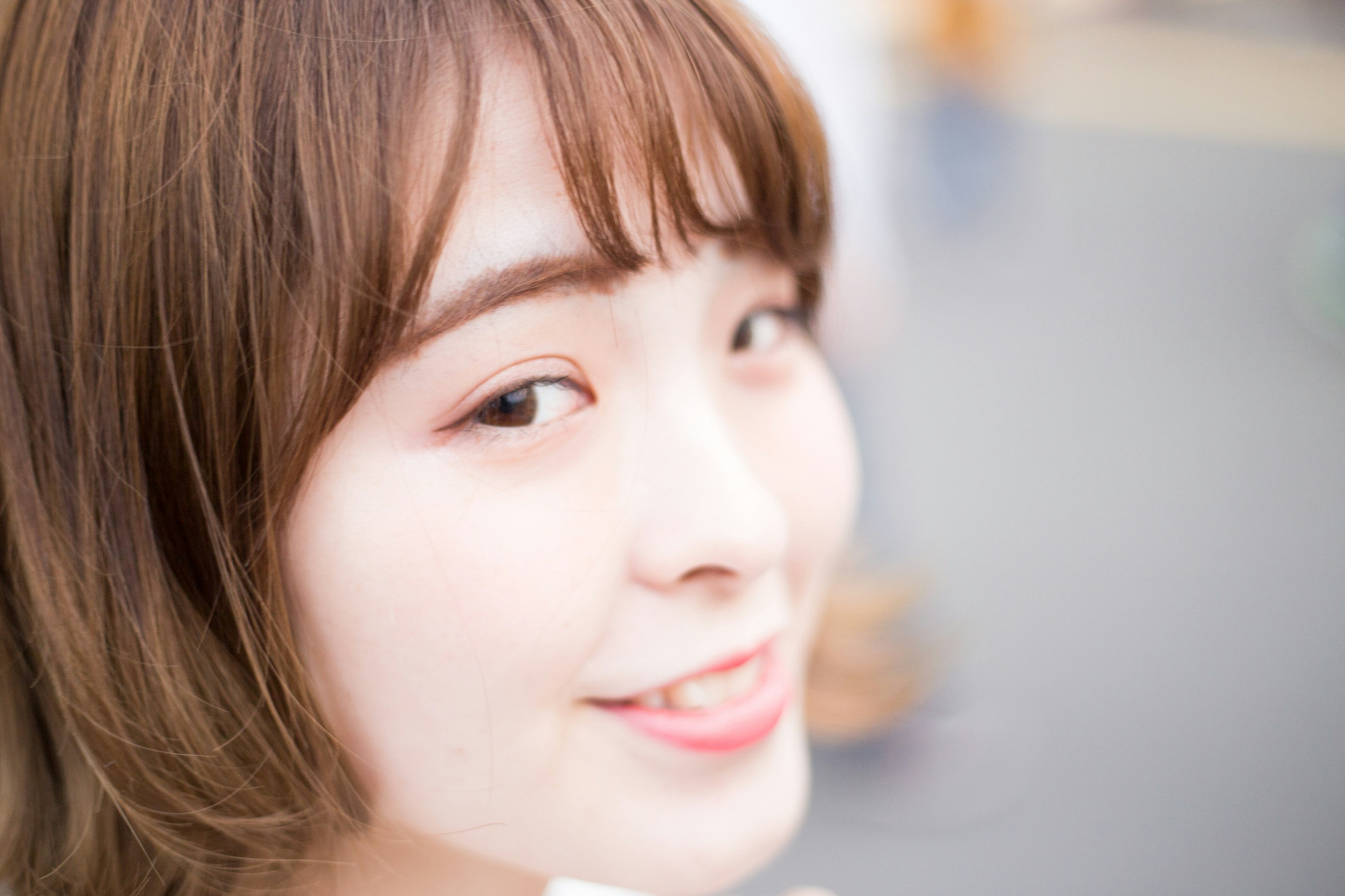 Close-up photo of a smiling woman with a bright expression and soft hair color