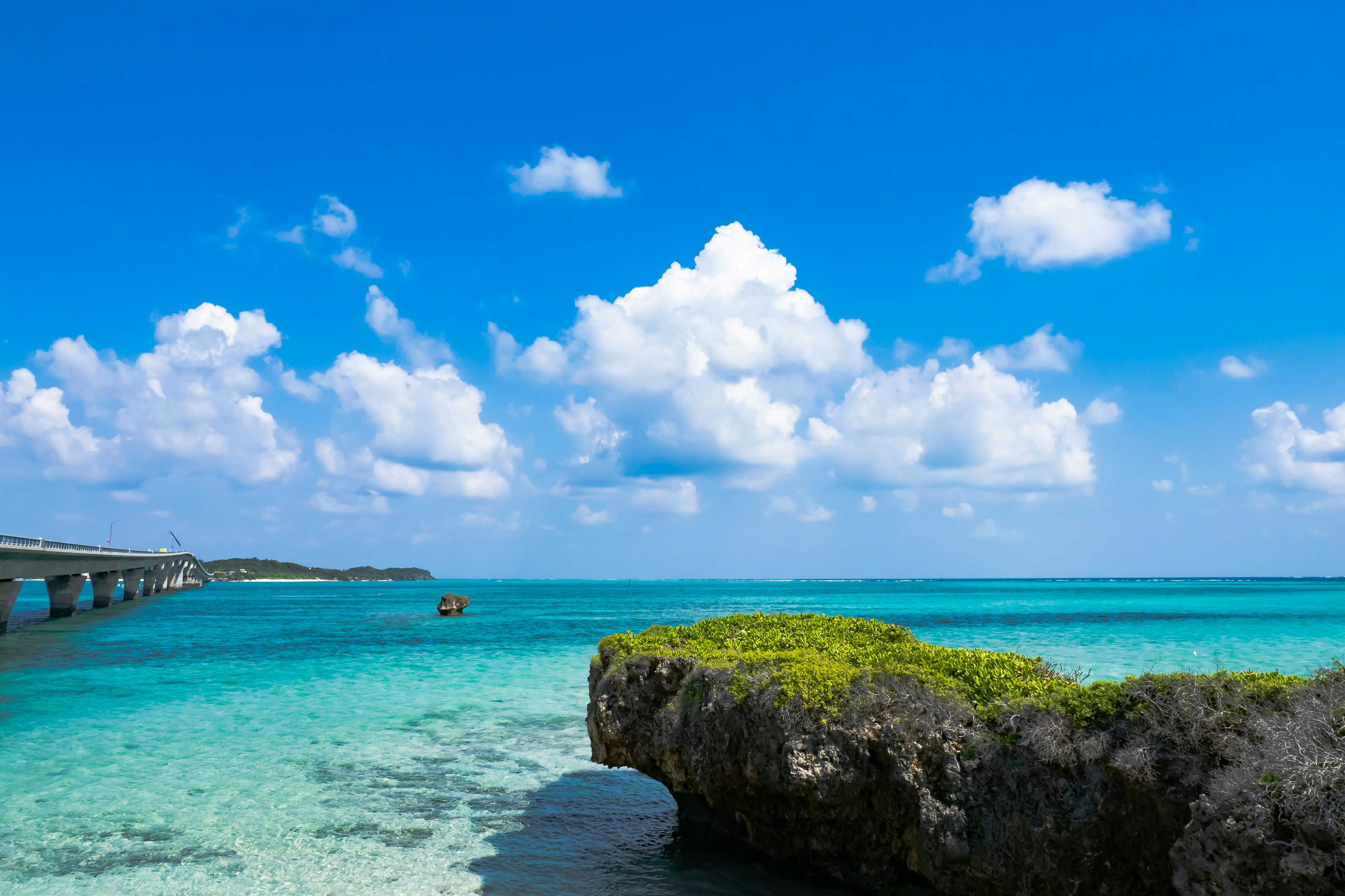 美丽的蓝色海洋和白色云朵的风景，清澈的水和绿色岩石