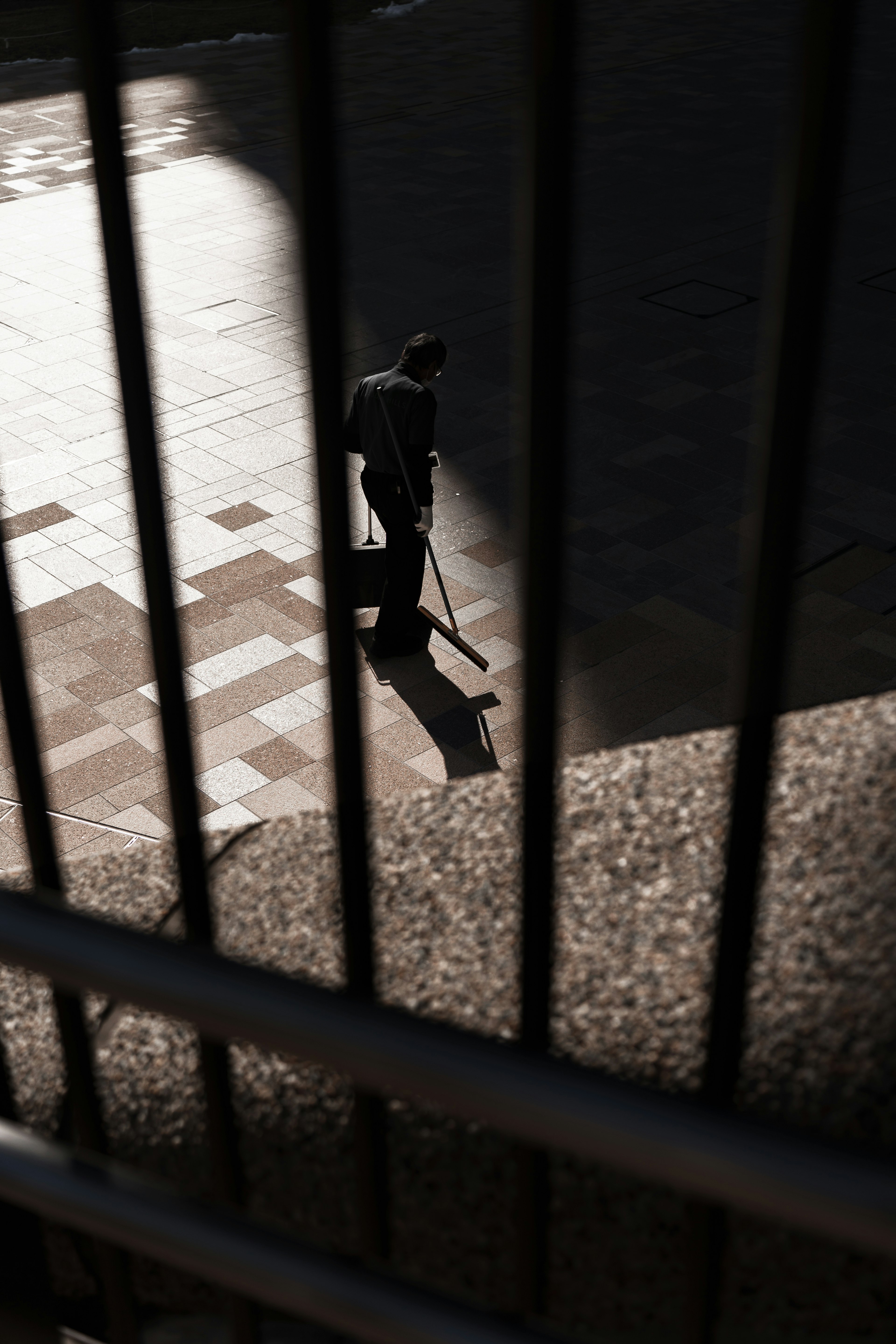 A person walking with a cane seen through iron bars