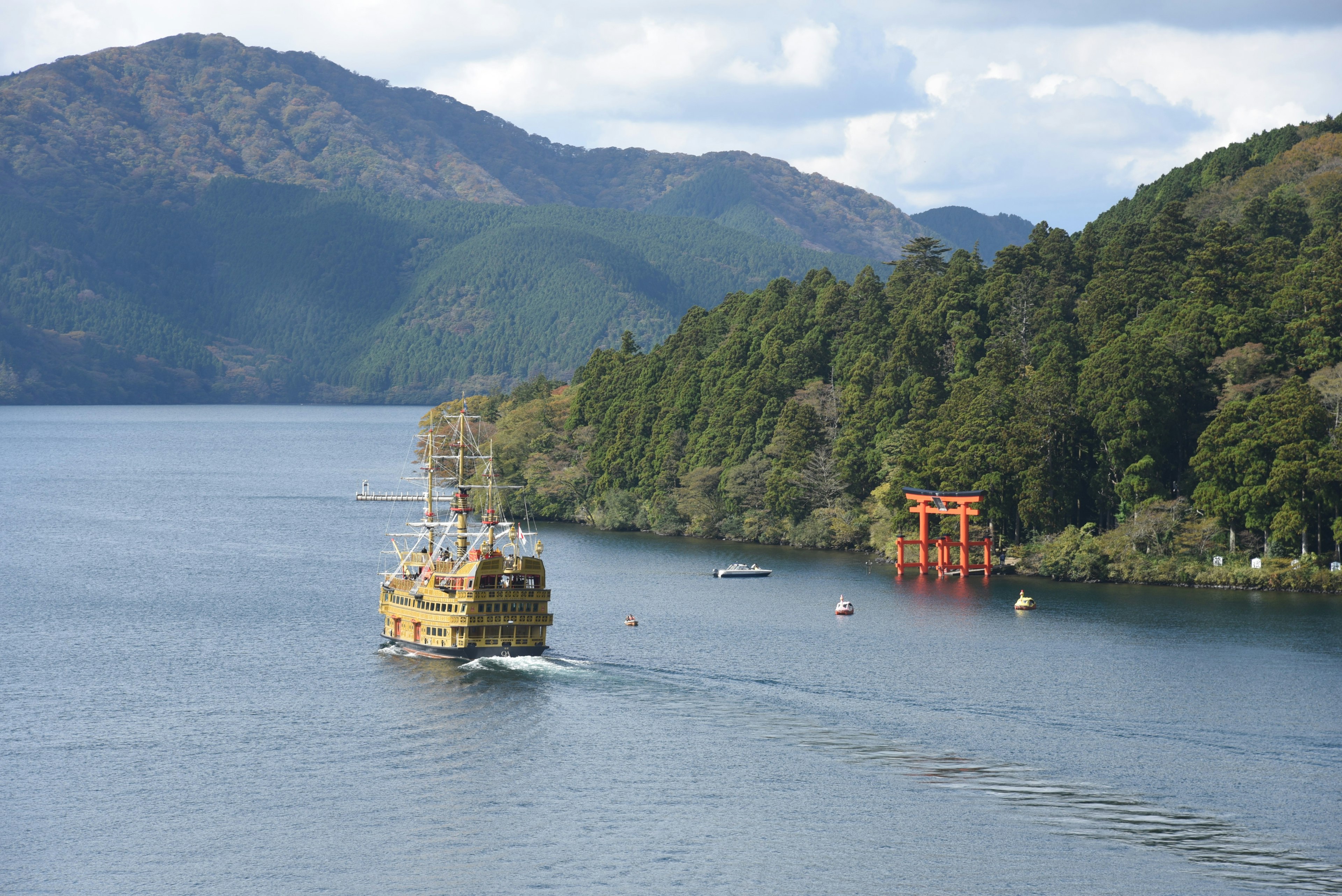 Malersicher Blick auf ein Schiff auf einem See umgeben von Bergen und einem Torii