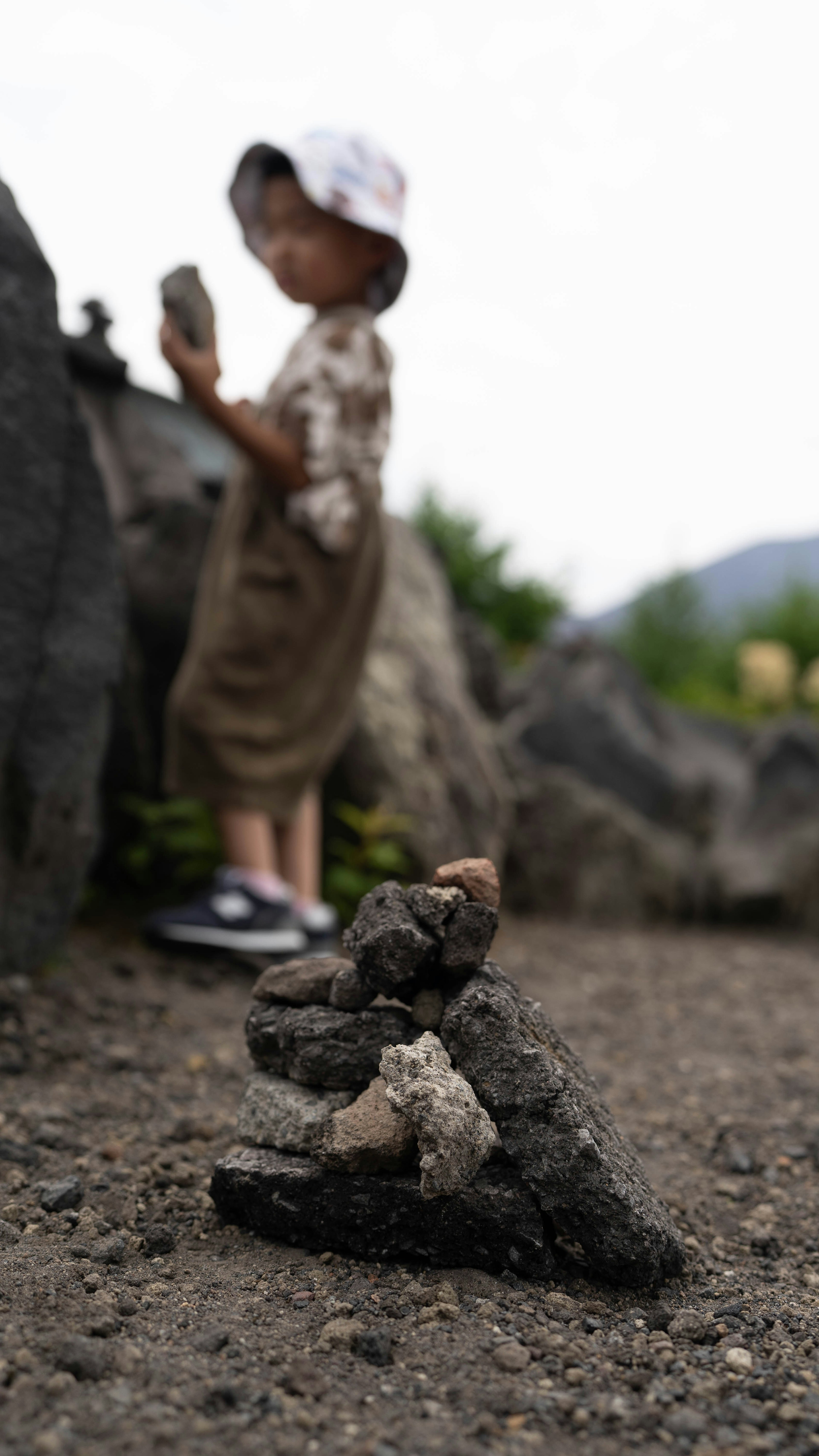 Una escena con una figura de niño cerca de rocas con un fondo borroso