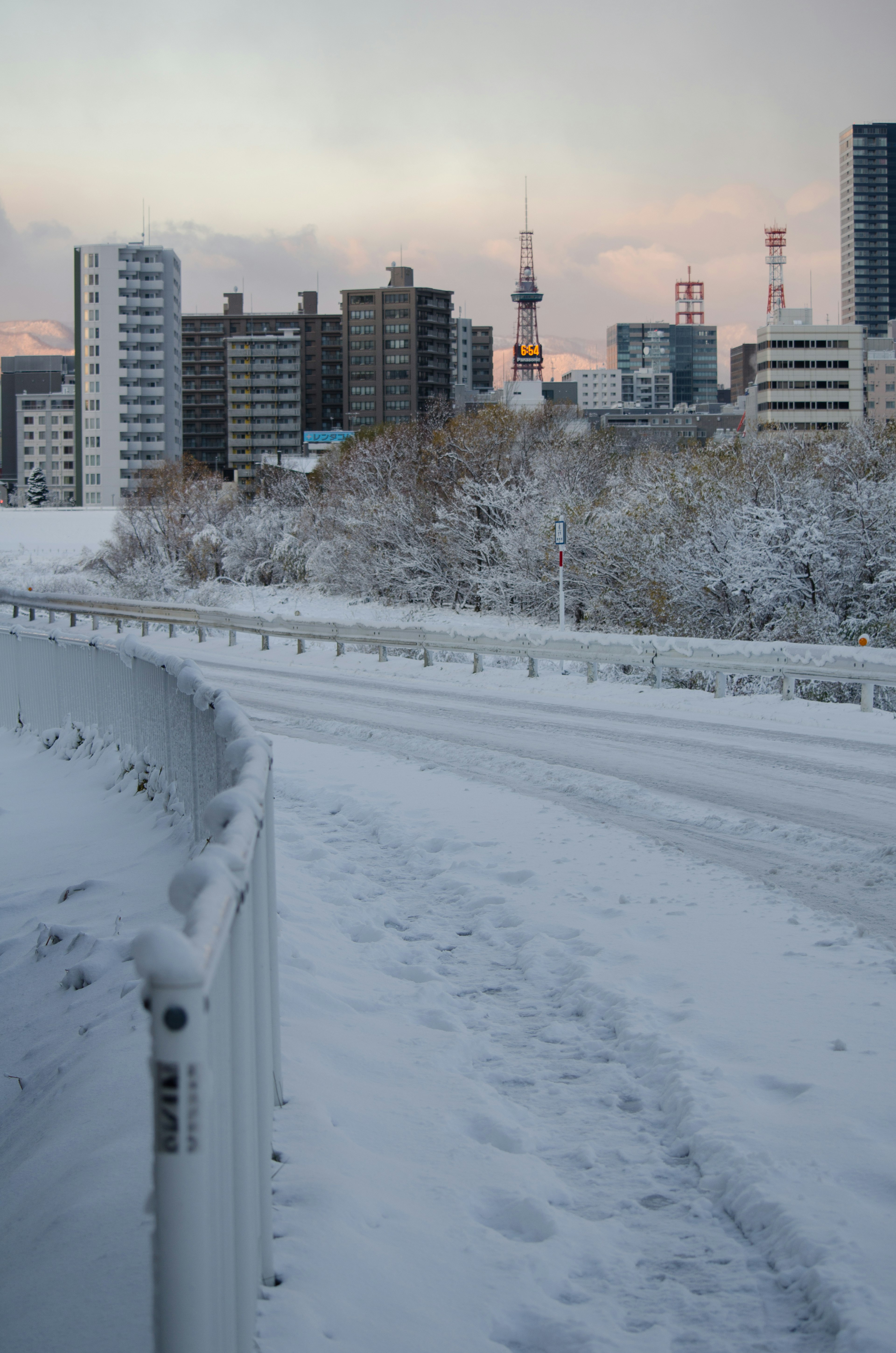 Snow-covered road with buildings in the background Soft evening light in winter