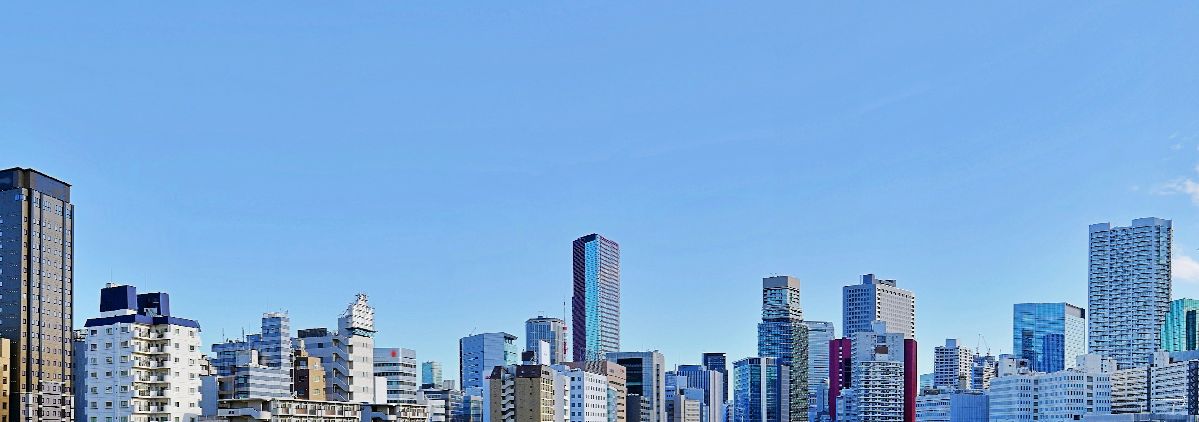 Urban skyline under a clear blue sky featuring various skyscrapers