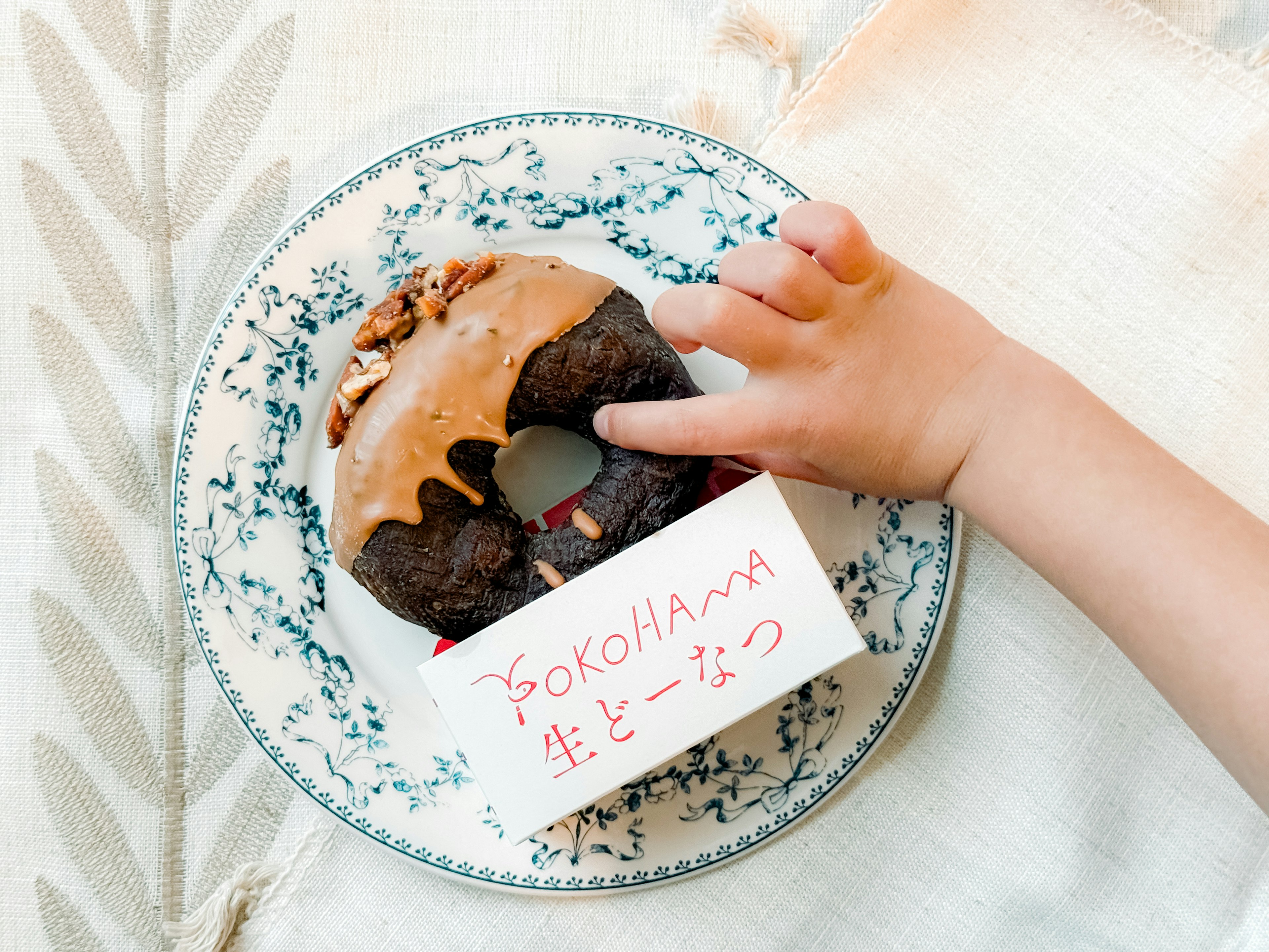 子供の手がチョコレートドーナツに触れている