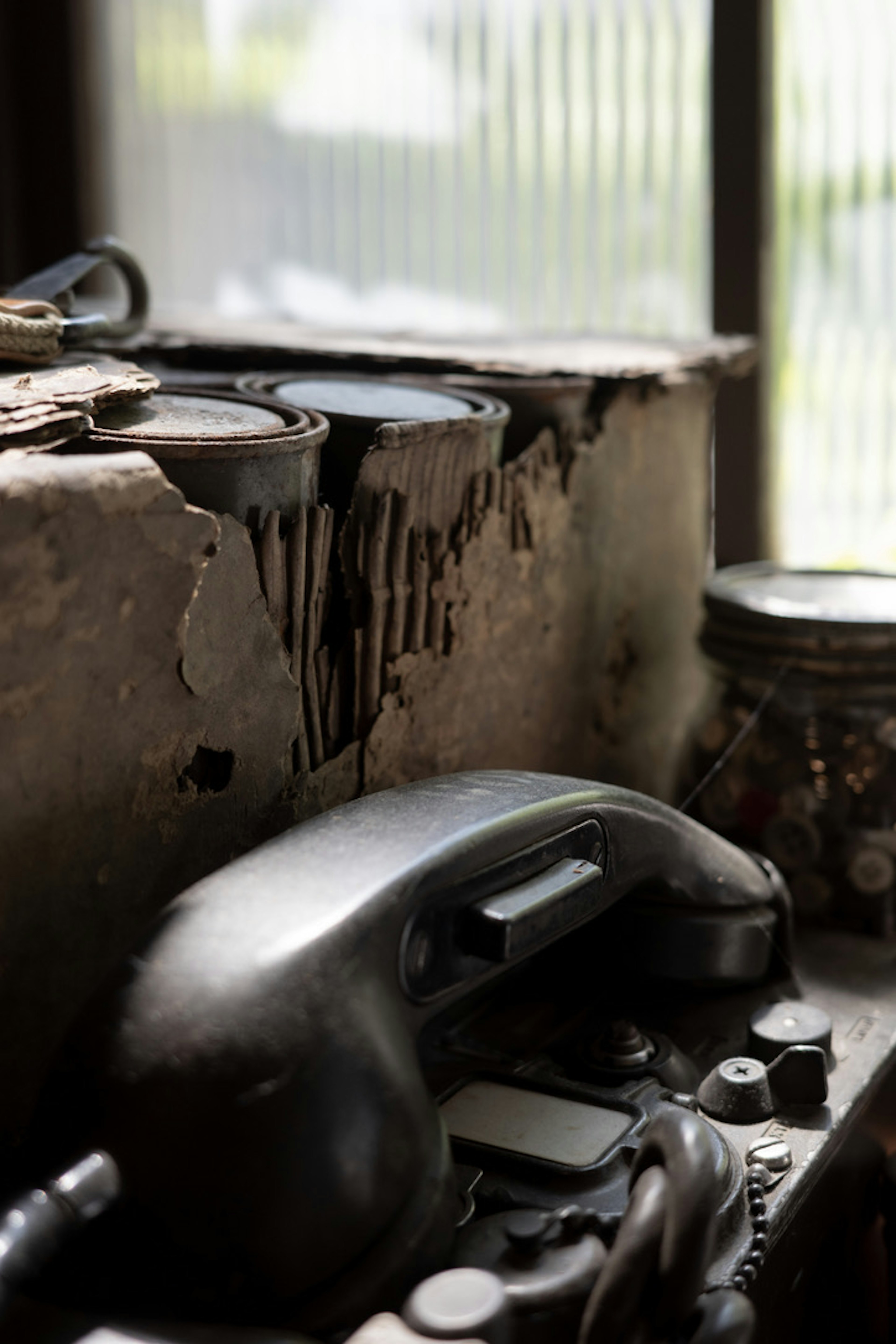 Vintage black telephone next to rusty cans