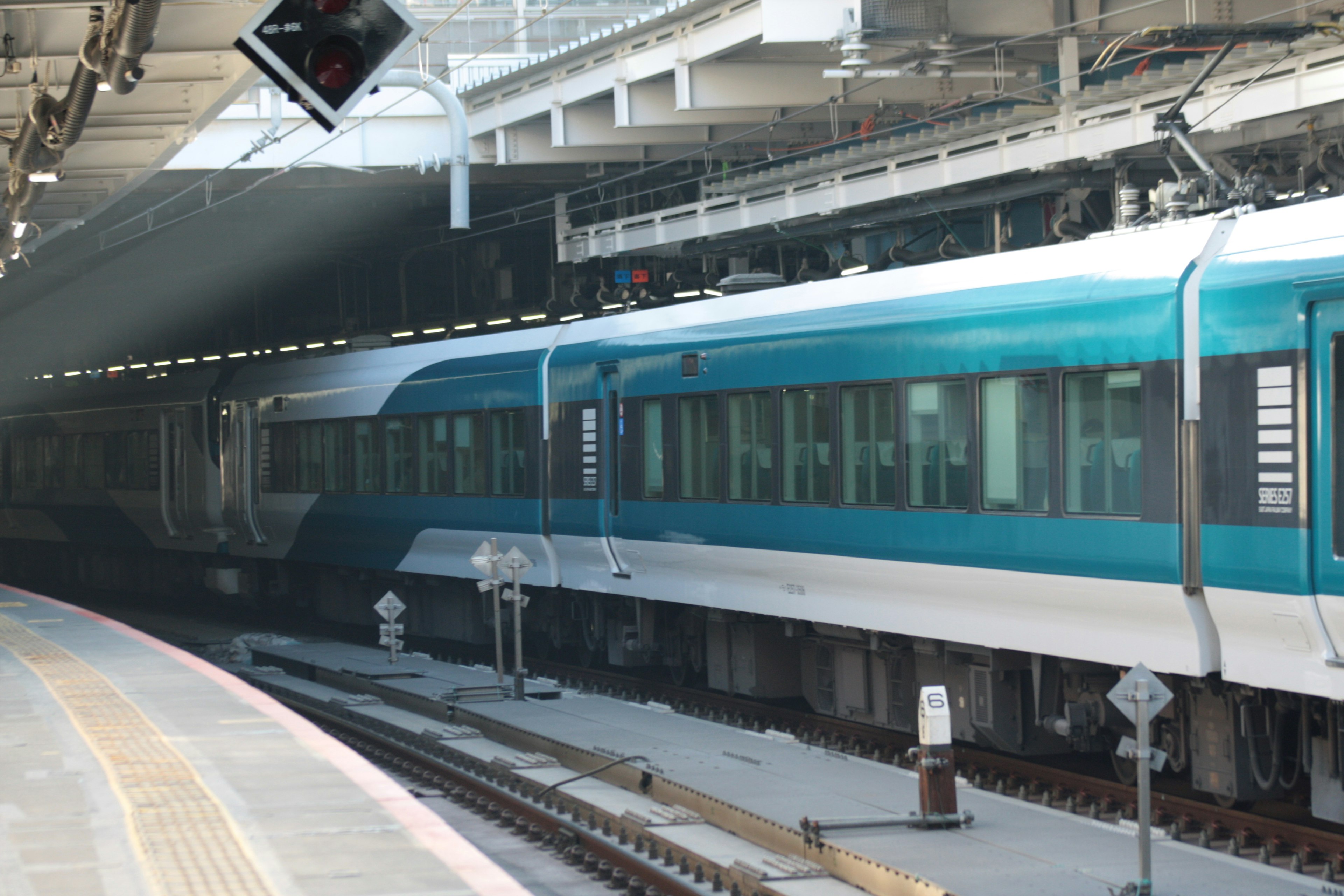 A blue train car is stopped at a train station platform