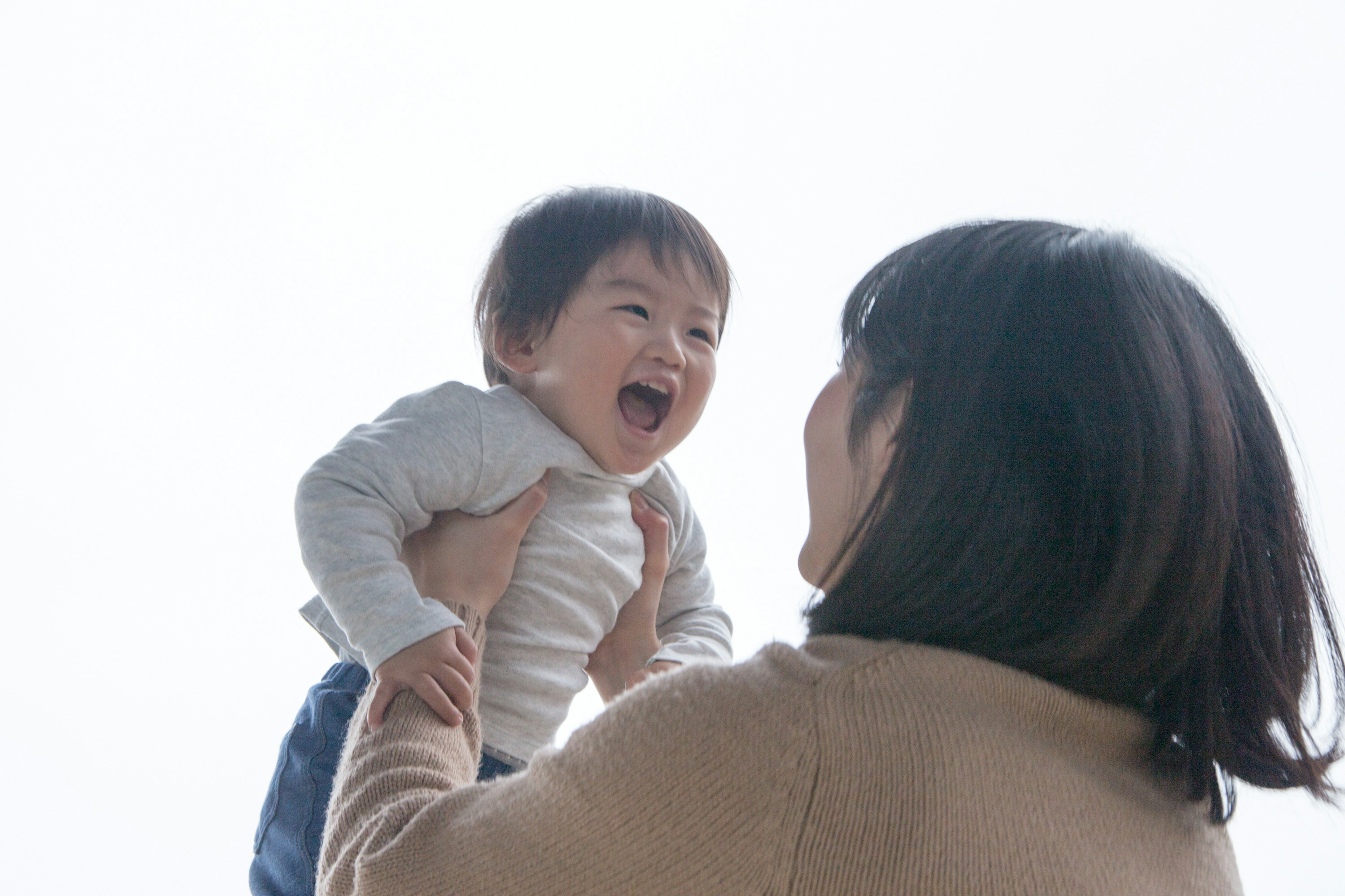 A baby laughing while being held by a mother