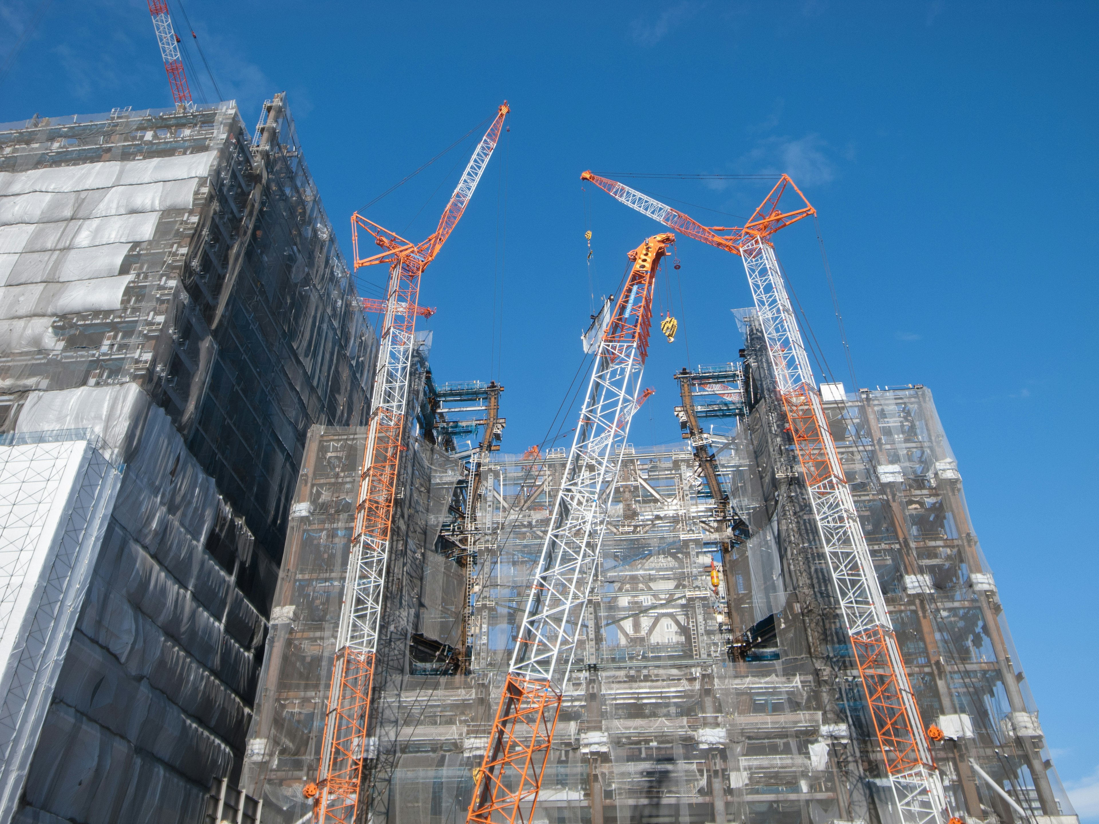 Site de construction avec grues et échafaudages sous un ciel bleu clair