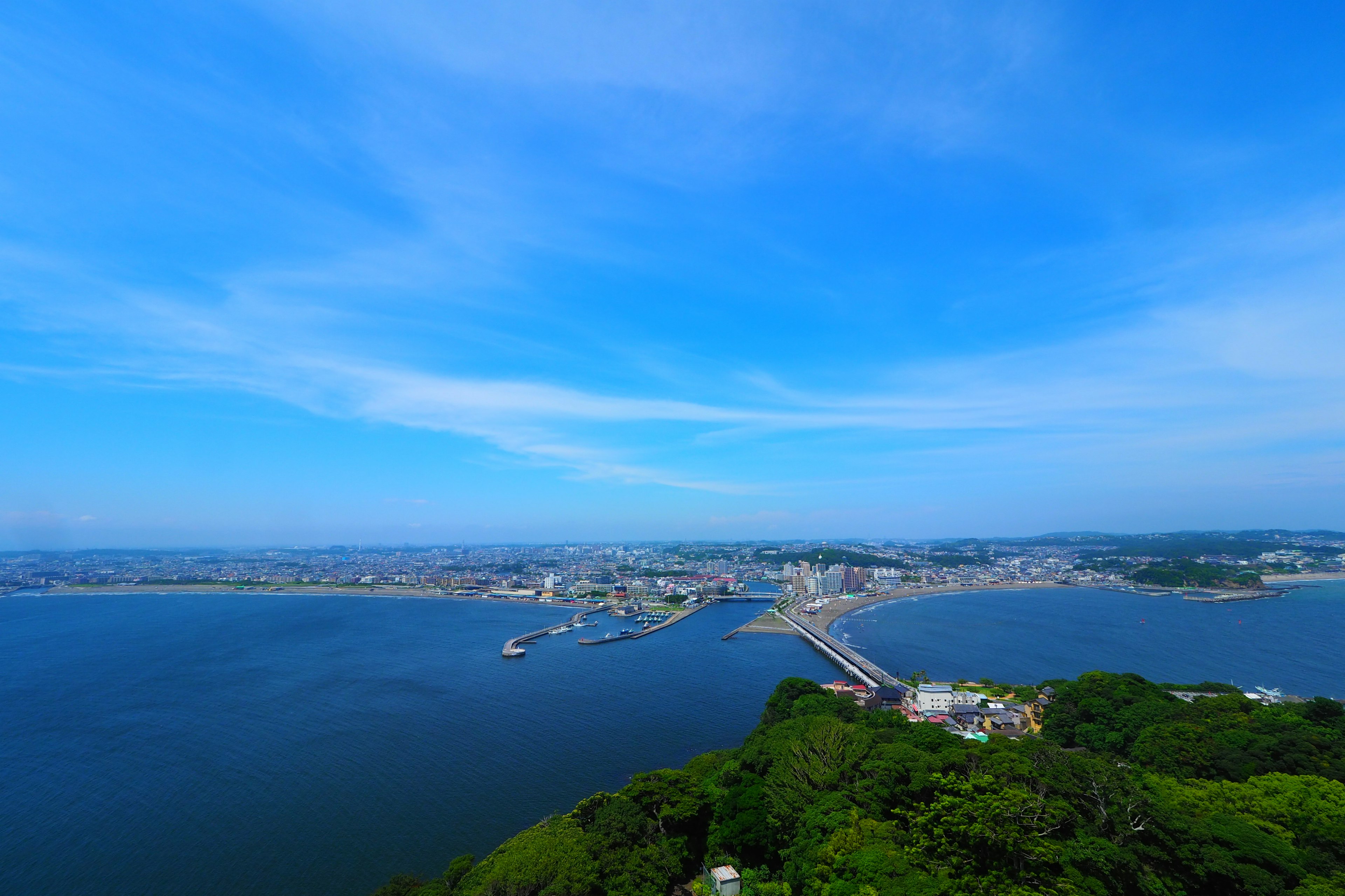 Scenic view of blue sky and ocean featuring a bridge and city