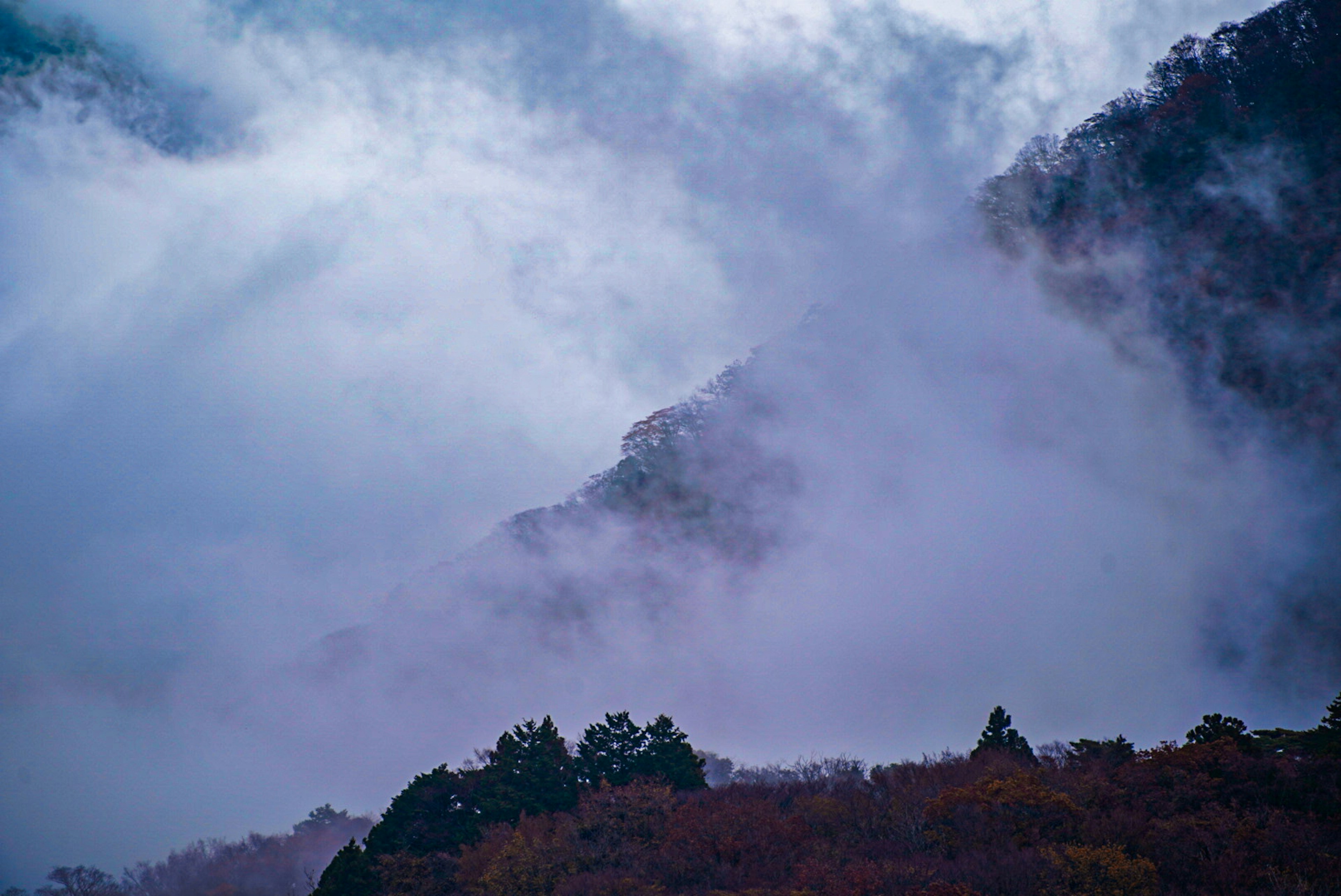 Berglandschaft in Nebel gehüllt mit schönem Kontrast zwischen blauem Himmel und Wolken