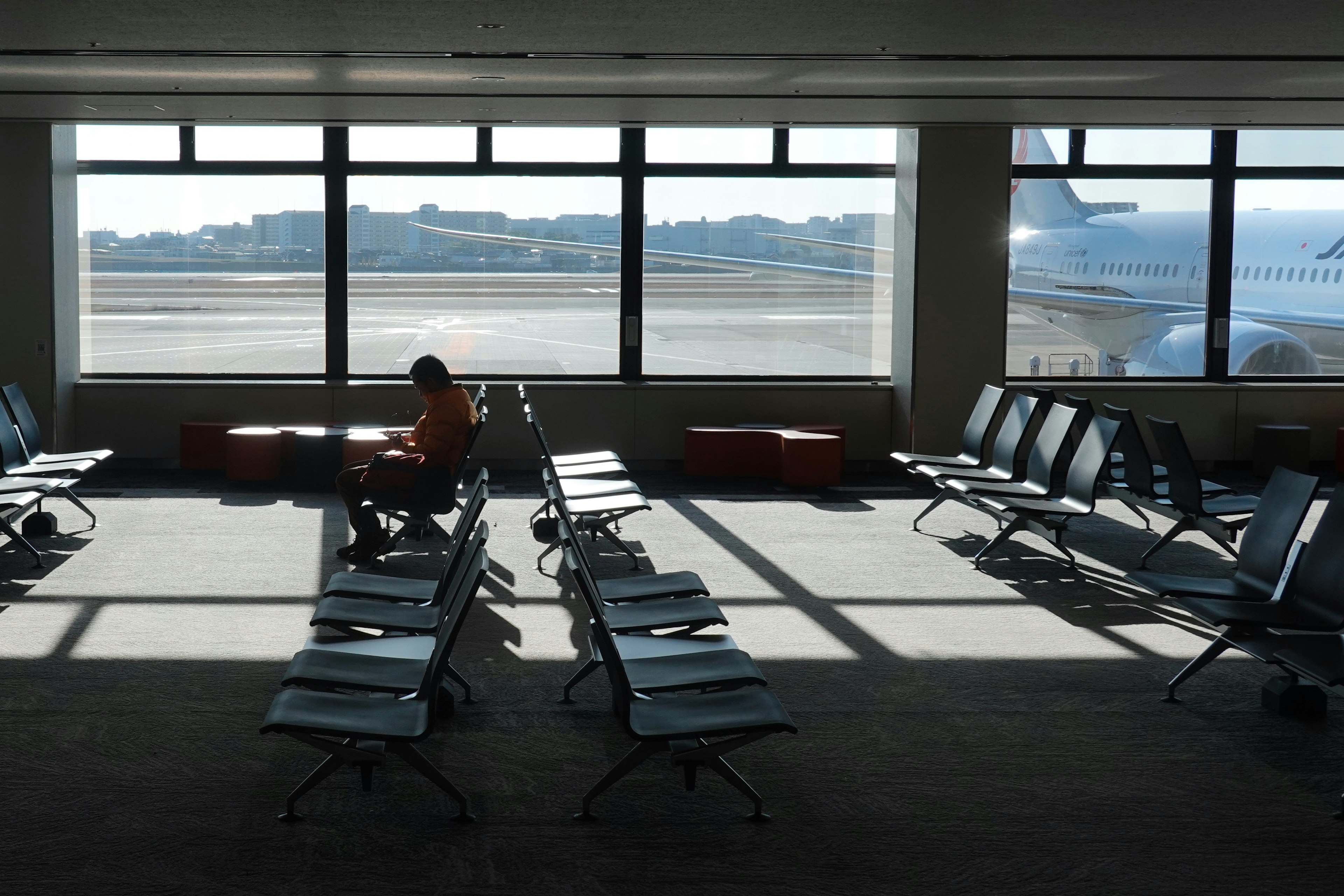 Quiet airport waiting room with natural light and shadows from large windows