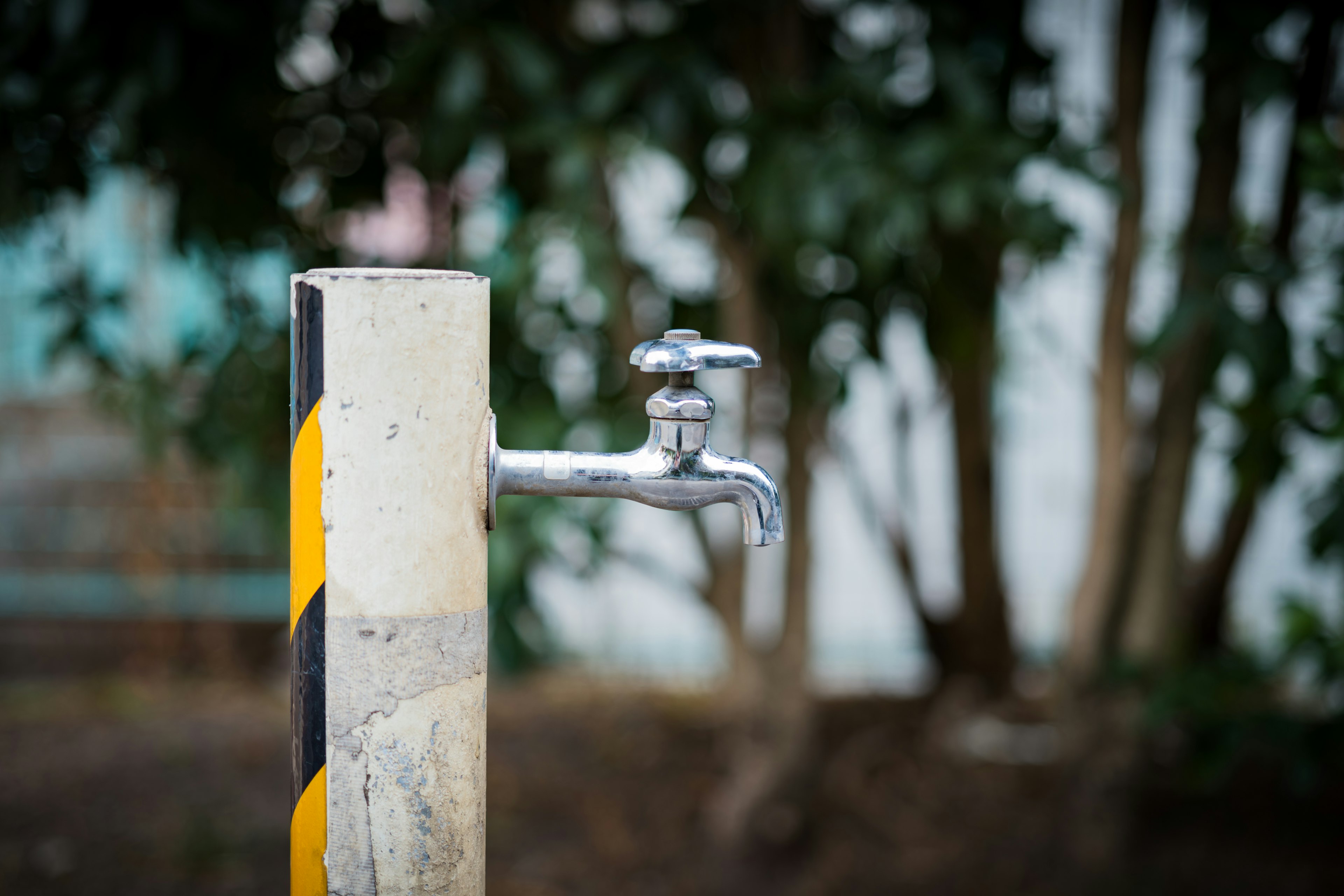 Wasserhahn, der aus einem gestreiften Rohr mit gelben und schwarzen Markierungen ragt