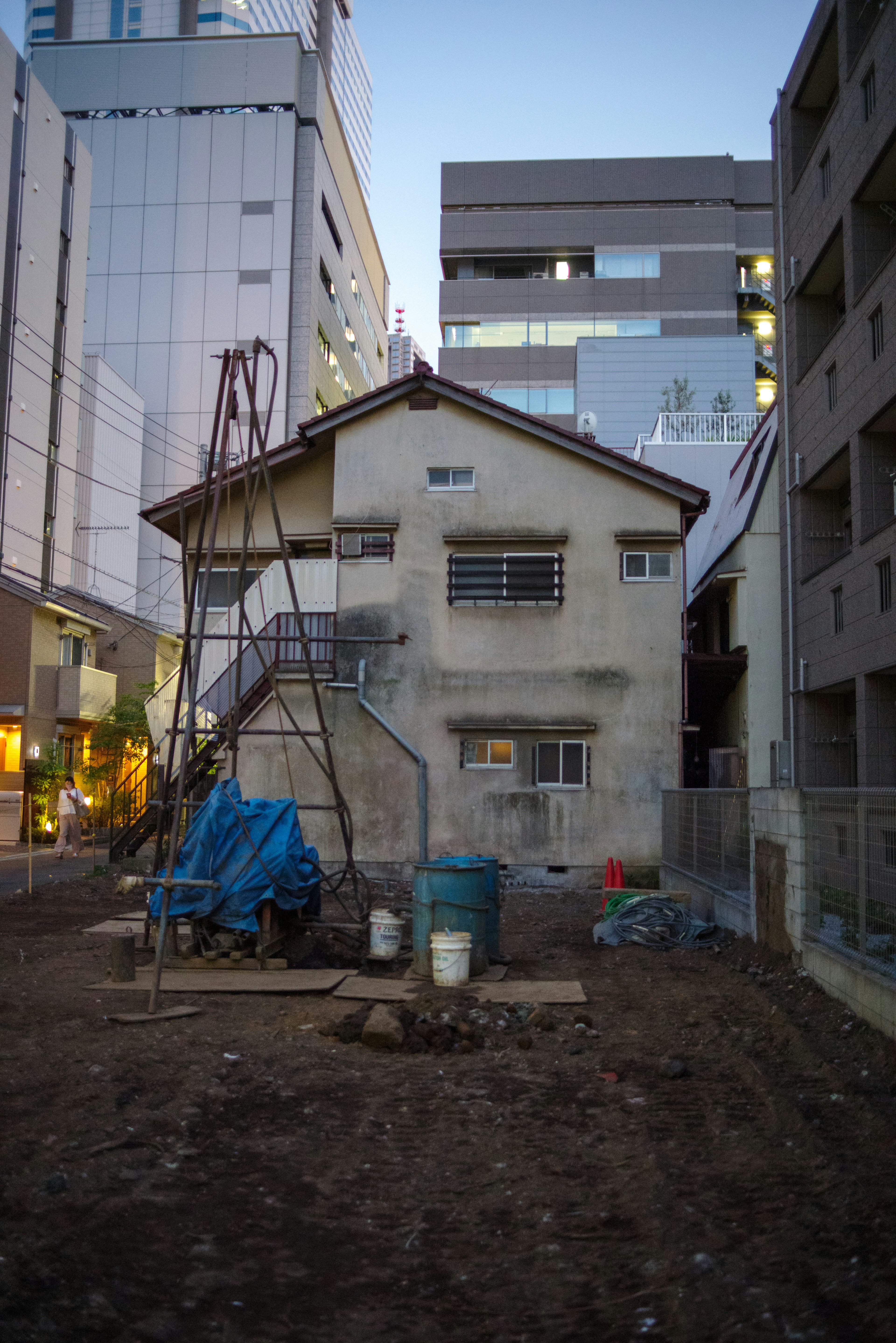 Vista nocturna de una casa antigua con un sitio de construcción en un entorno urbano