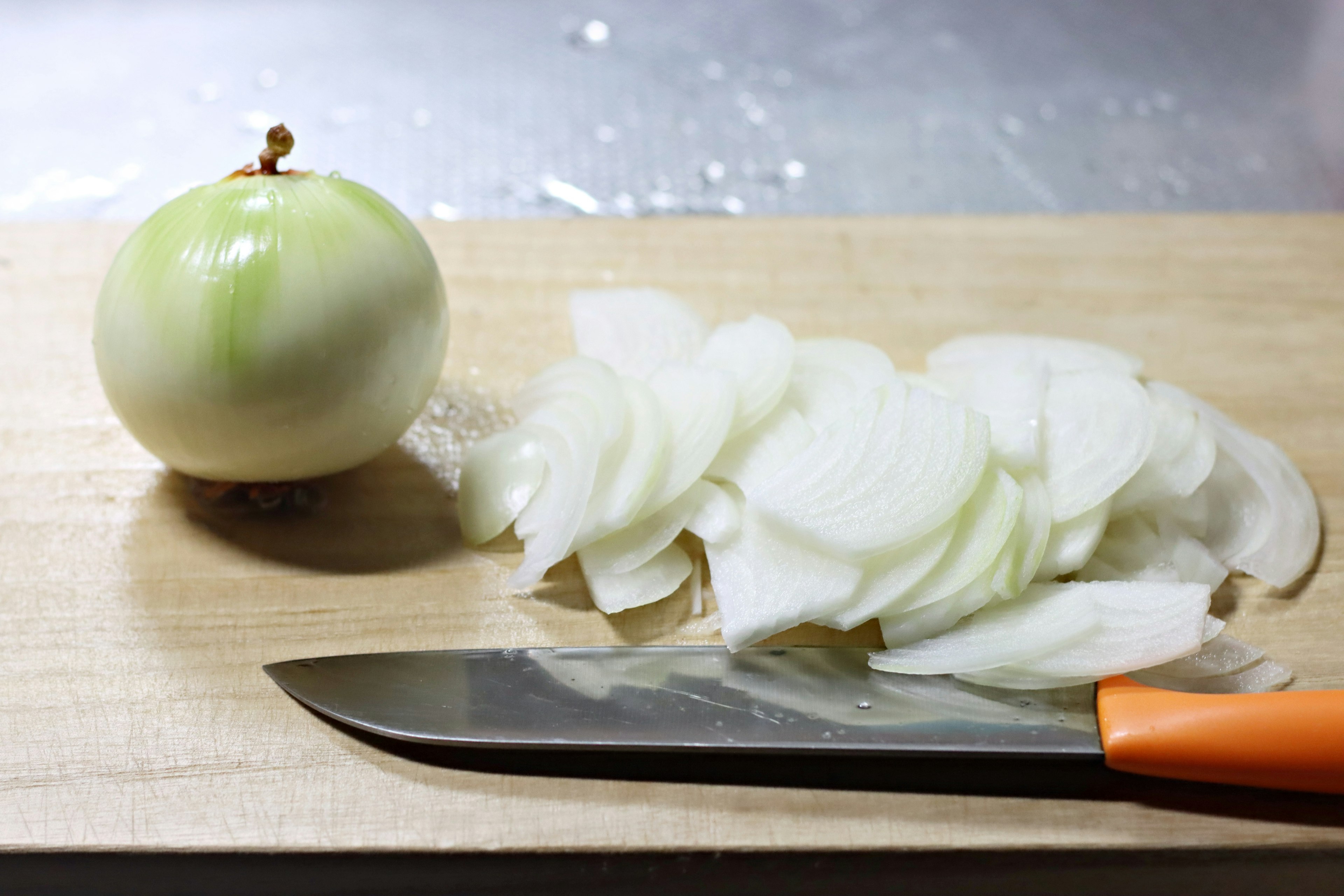 Whole onion and sliced onion on a wooden cutting board